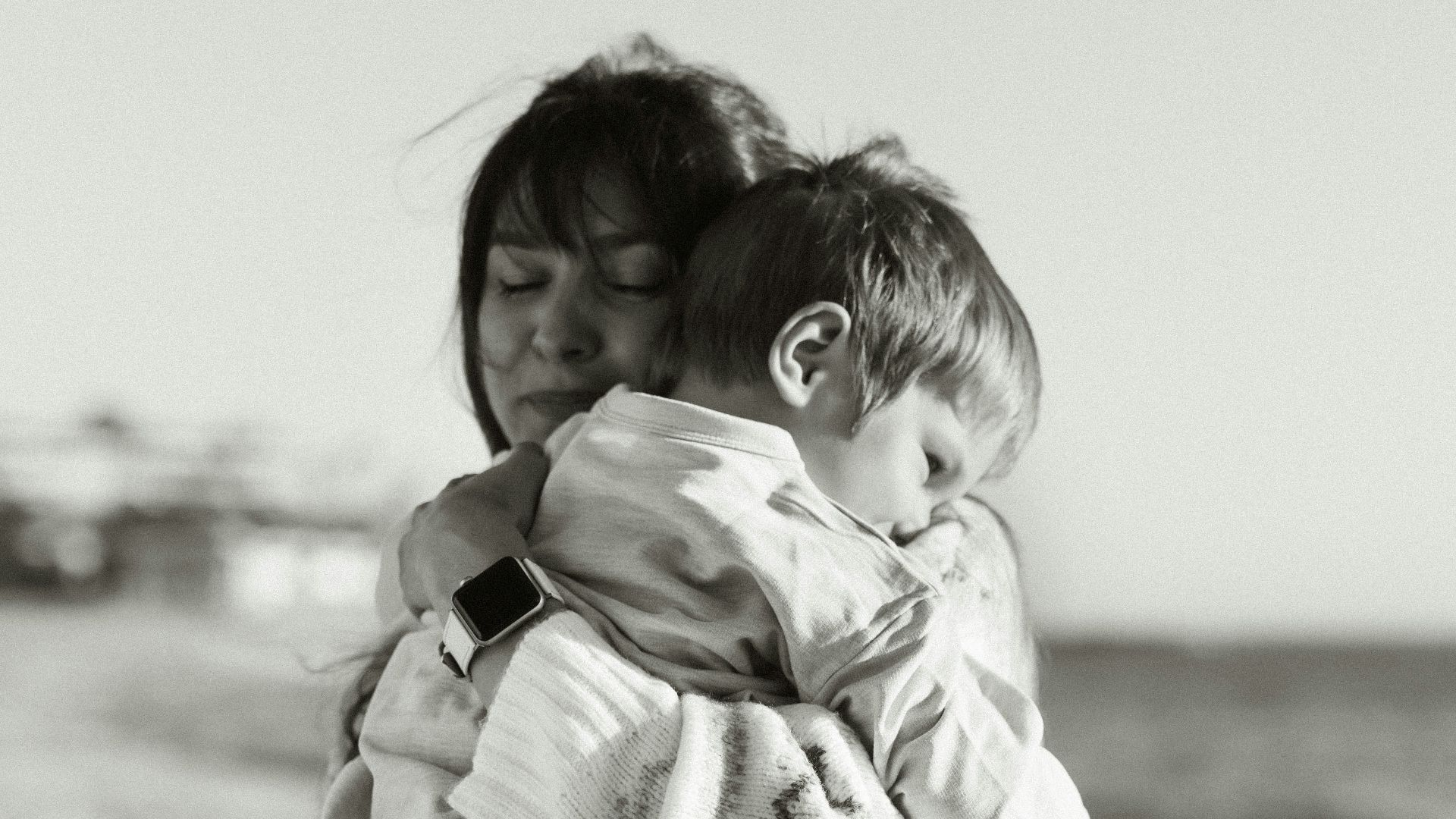 a woman carrying a child on the beach
