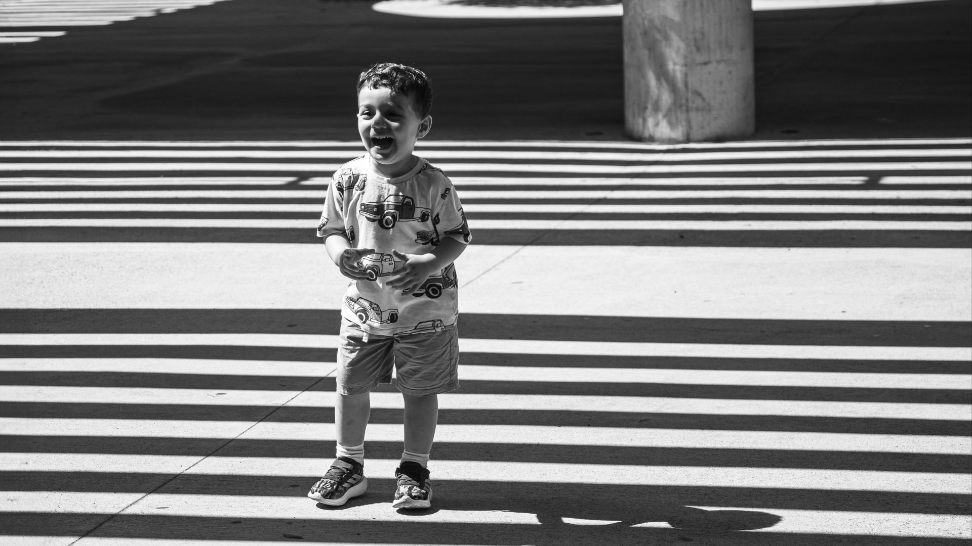 A child stands on a crosswalk in black and white.