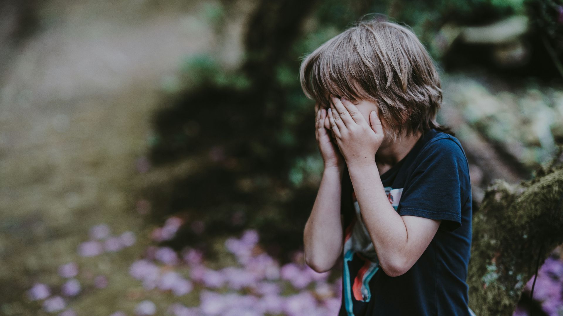 boy covering his face while standing