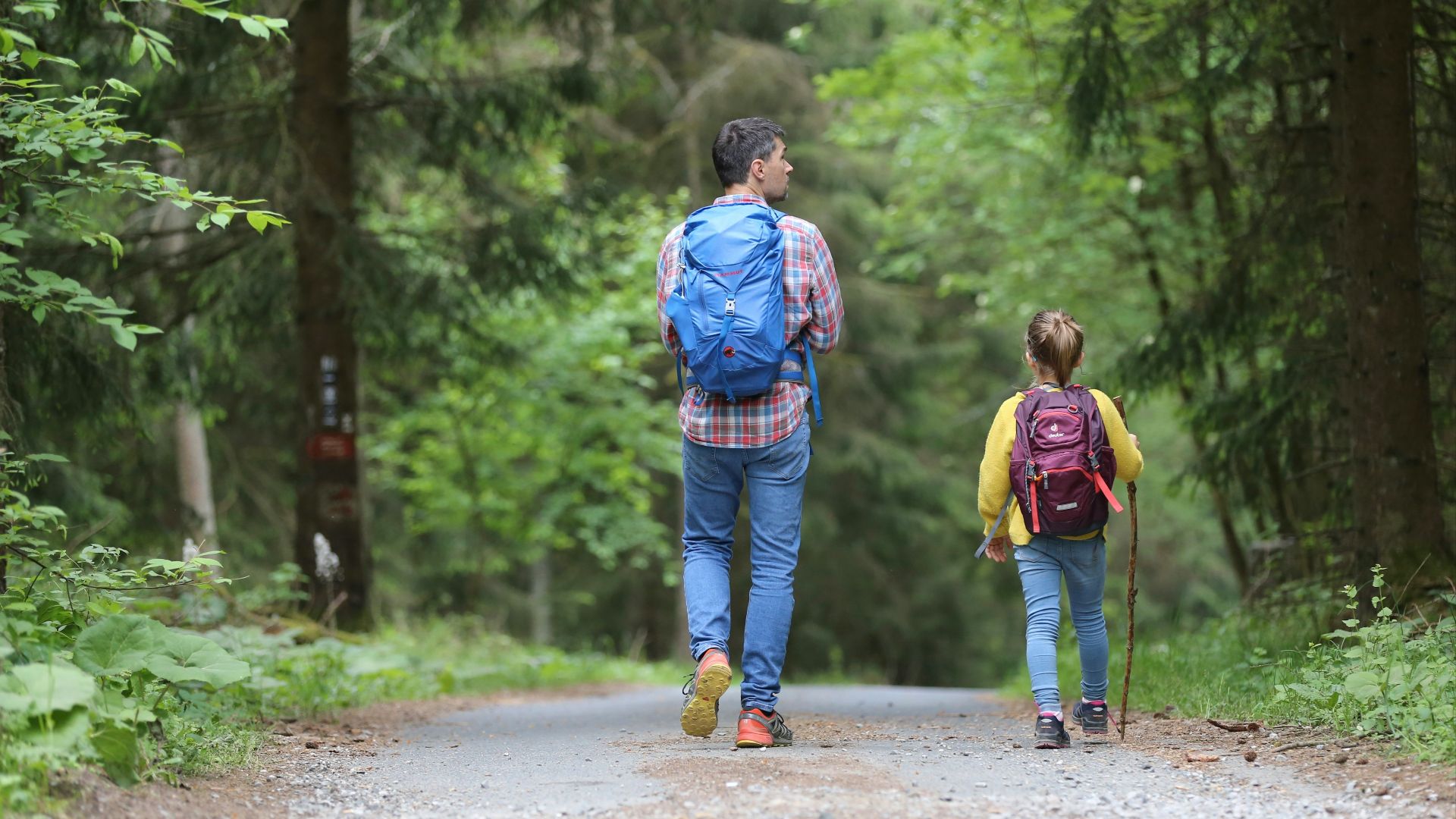 man in blue jacket and blue denim jeans walking on dirt road during daytime
