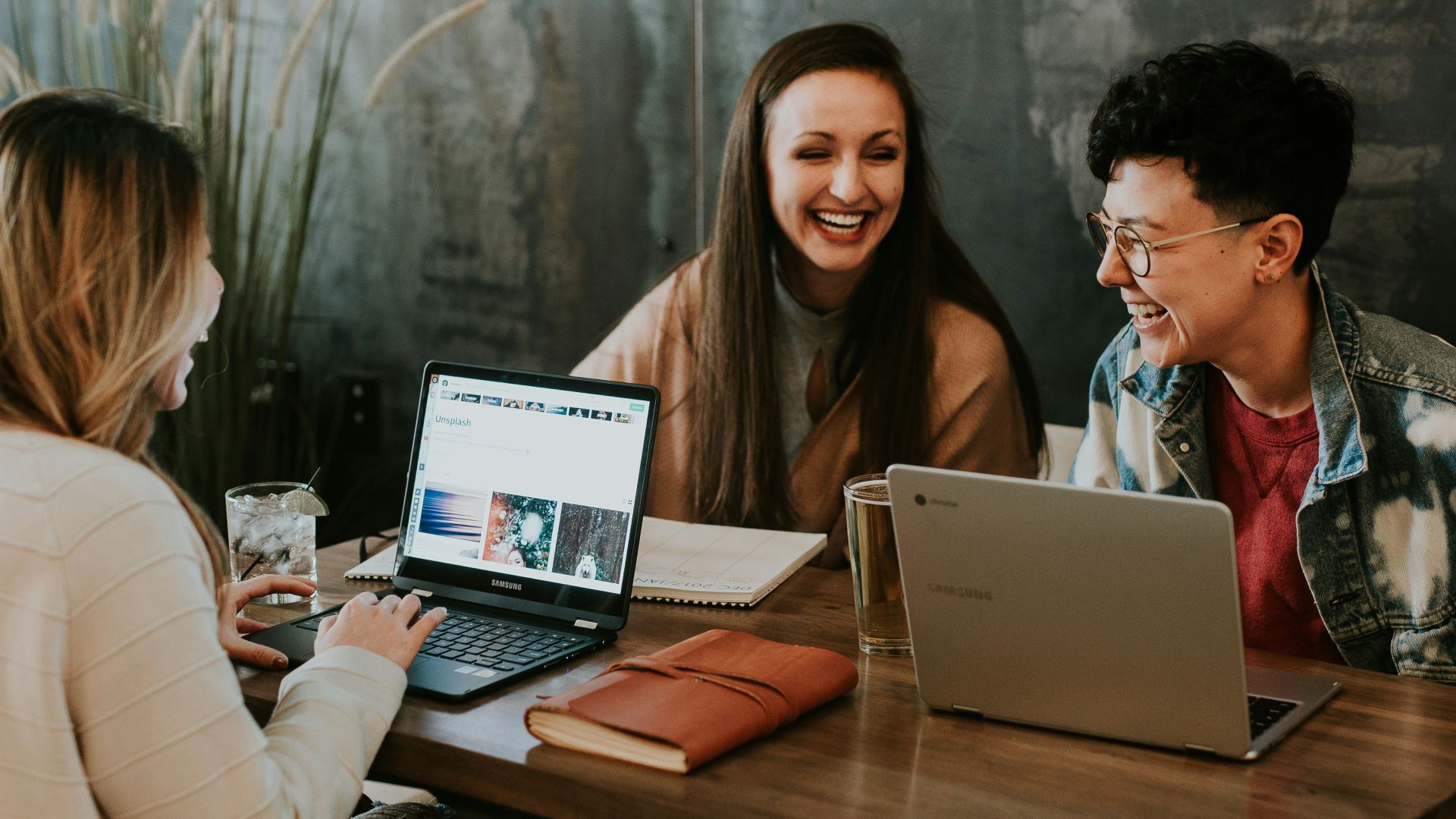 three people sitting in front of table laughing together