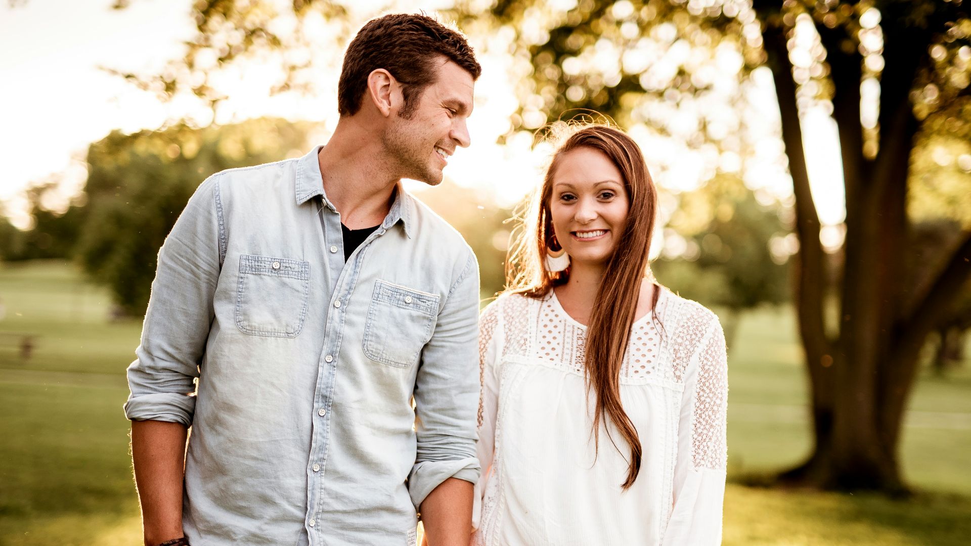 man holding hand of woman standing near tree