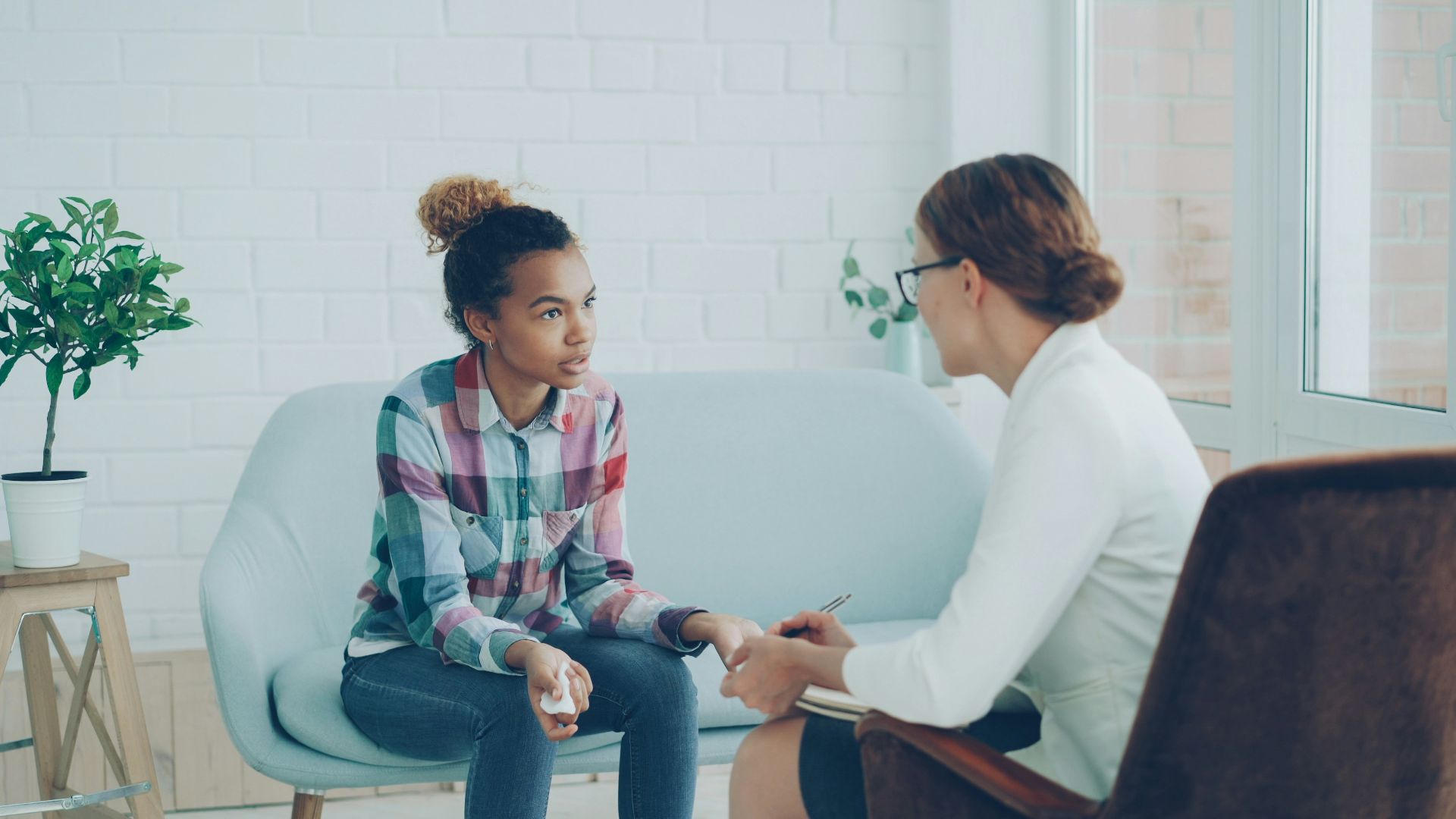 Therapist talking to a young woman on couch.