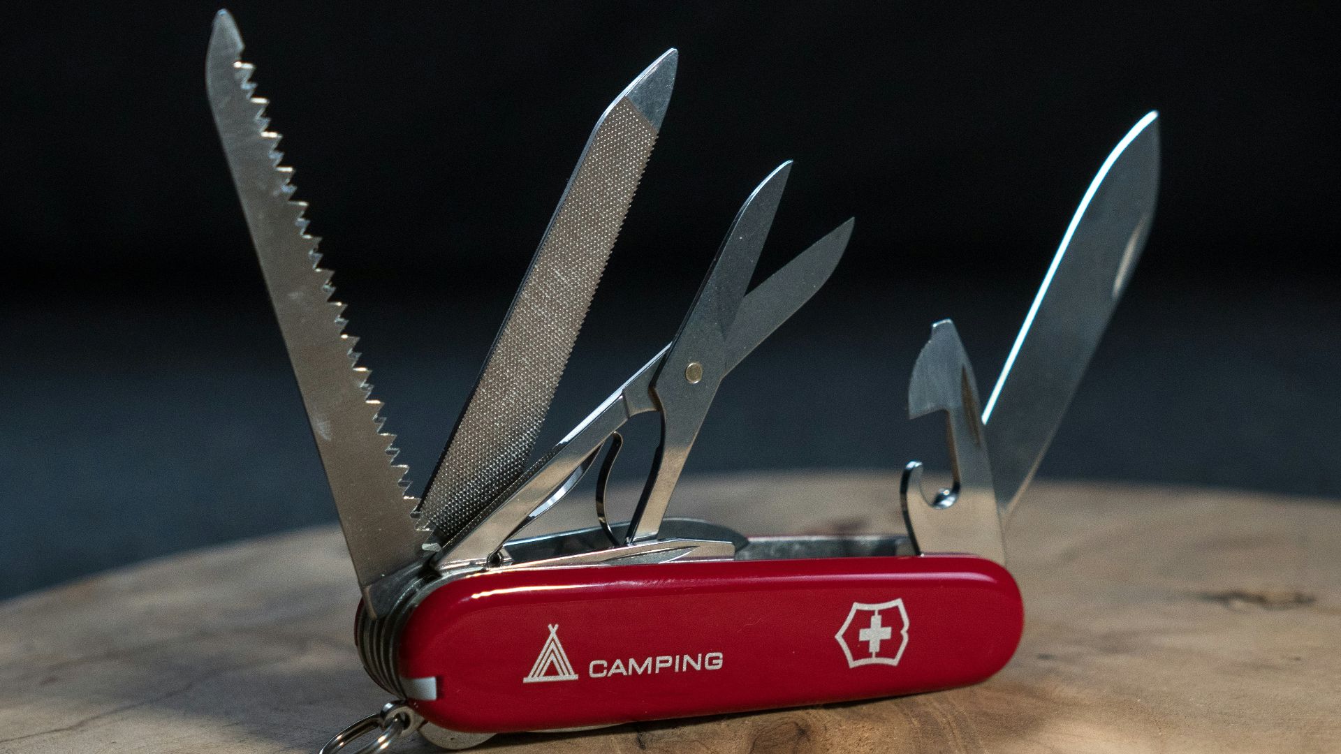 A red swiss army knife sitting on top of a wooden table