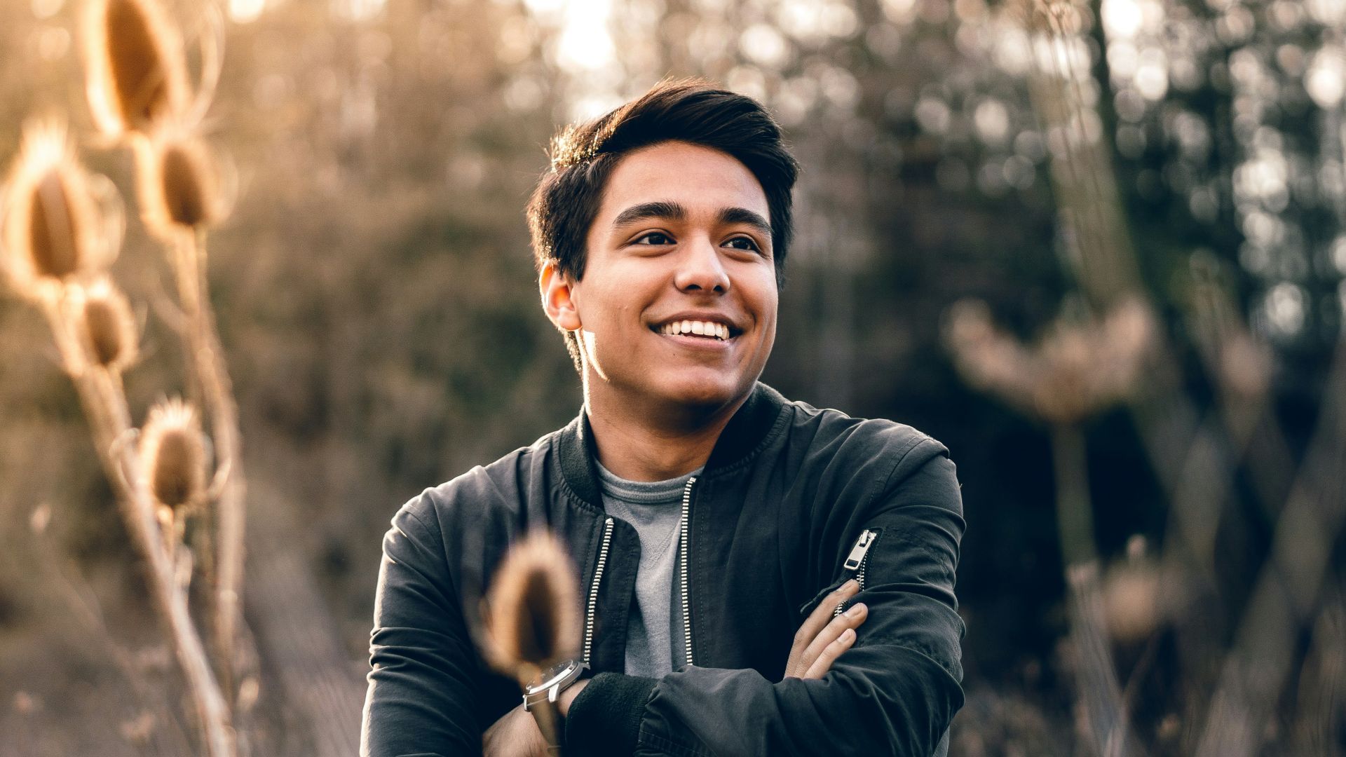 smiling man standing near green trees