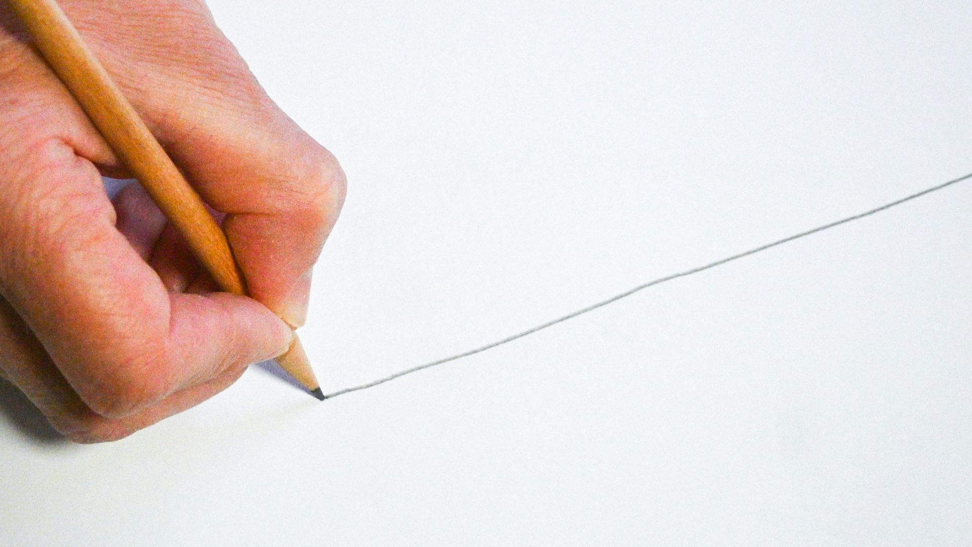 A person holding a pencil and writing on a piece of paper