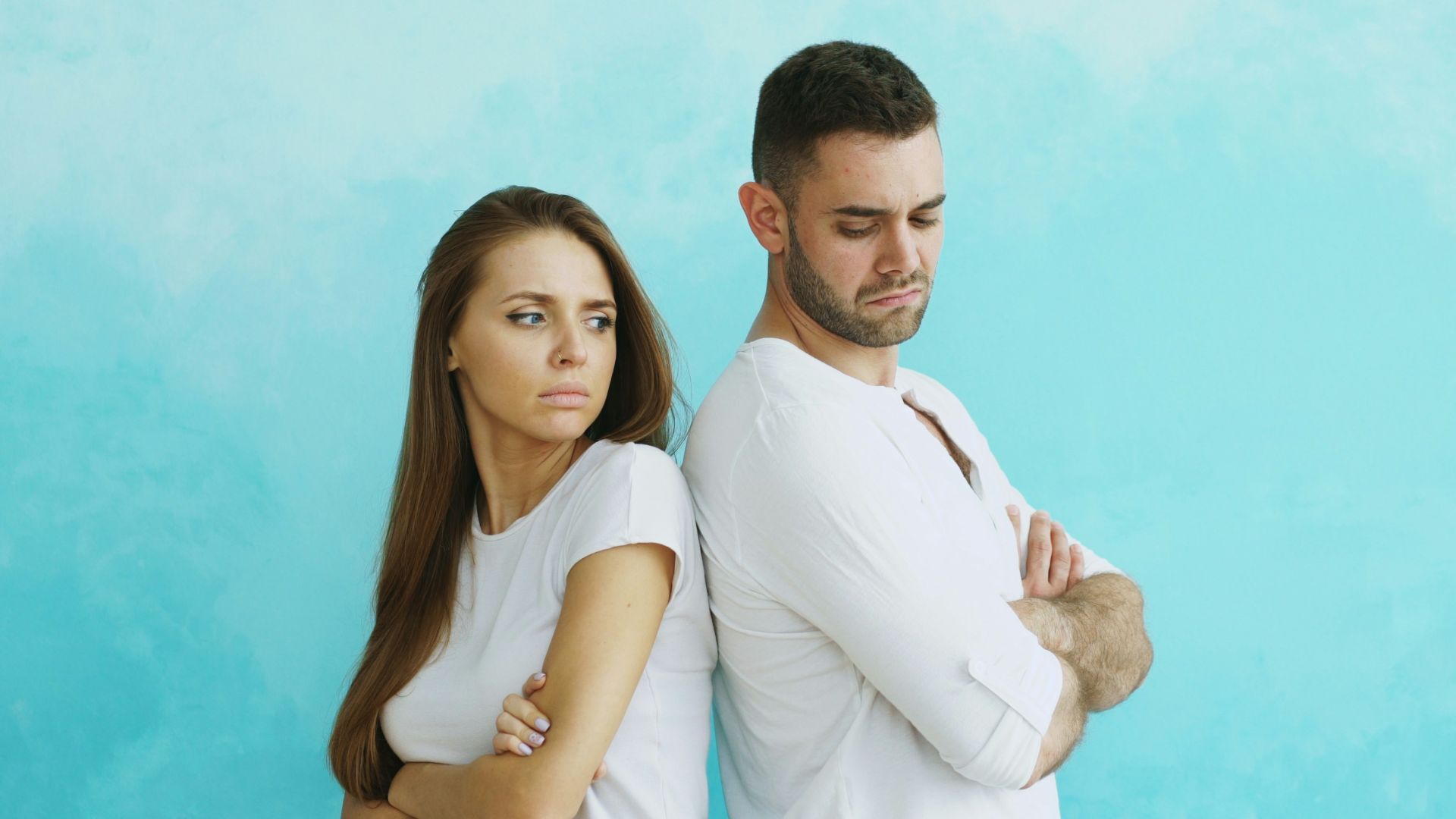 Couple standing back to back with arms crossed