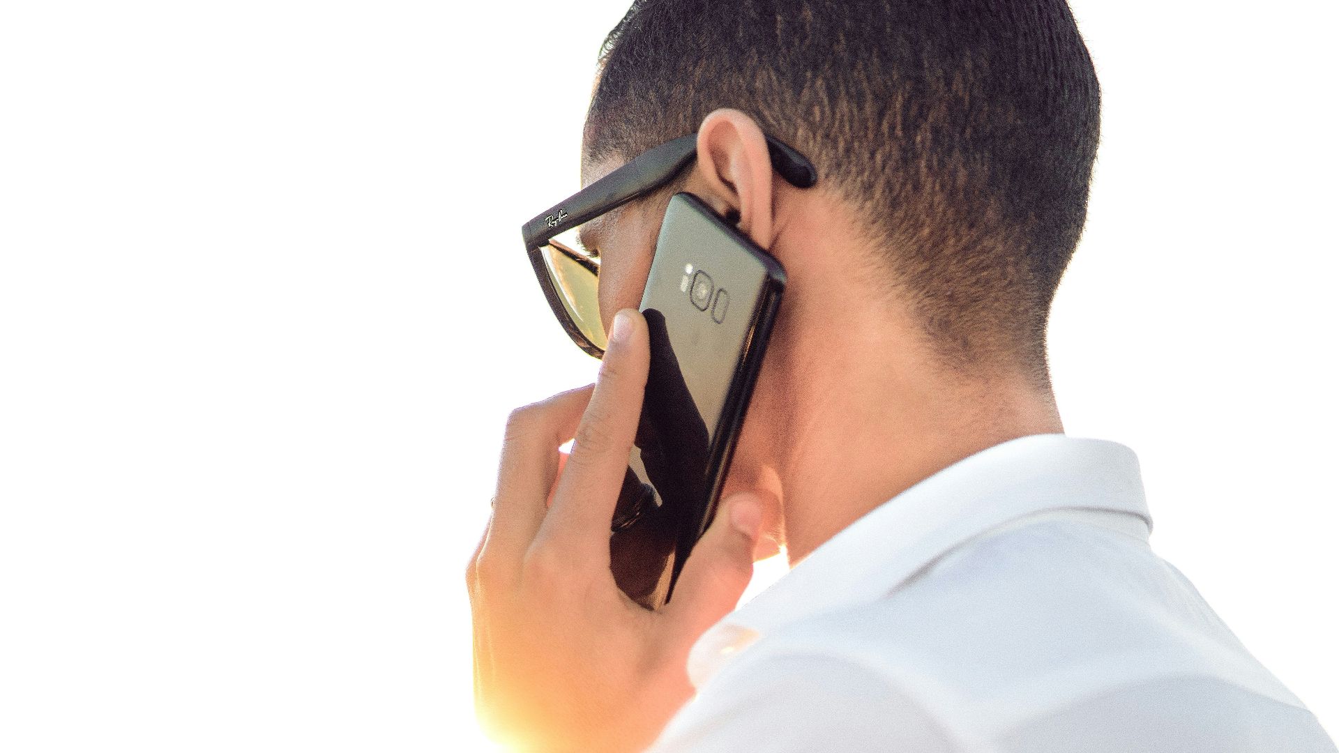 man holding smartphone standing in front of calm body of water