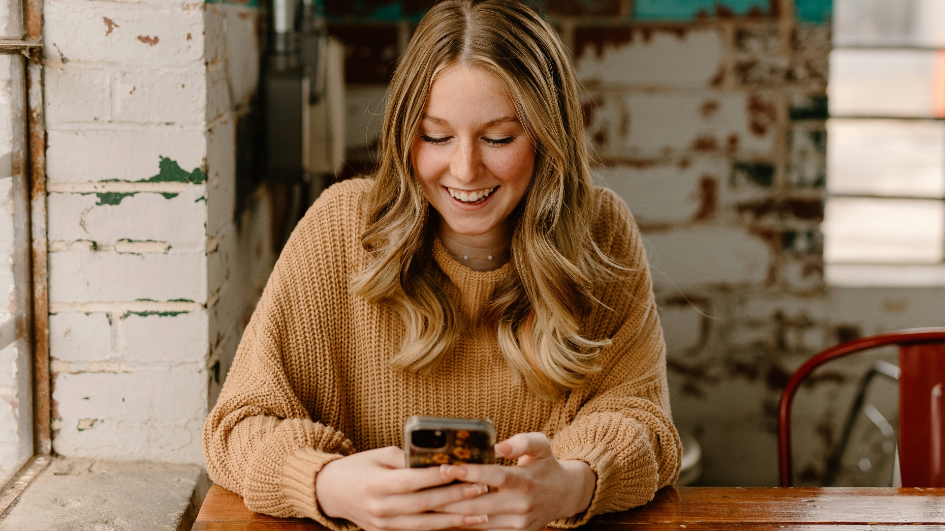 a woman sitting at a table looking at her cell phone