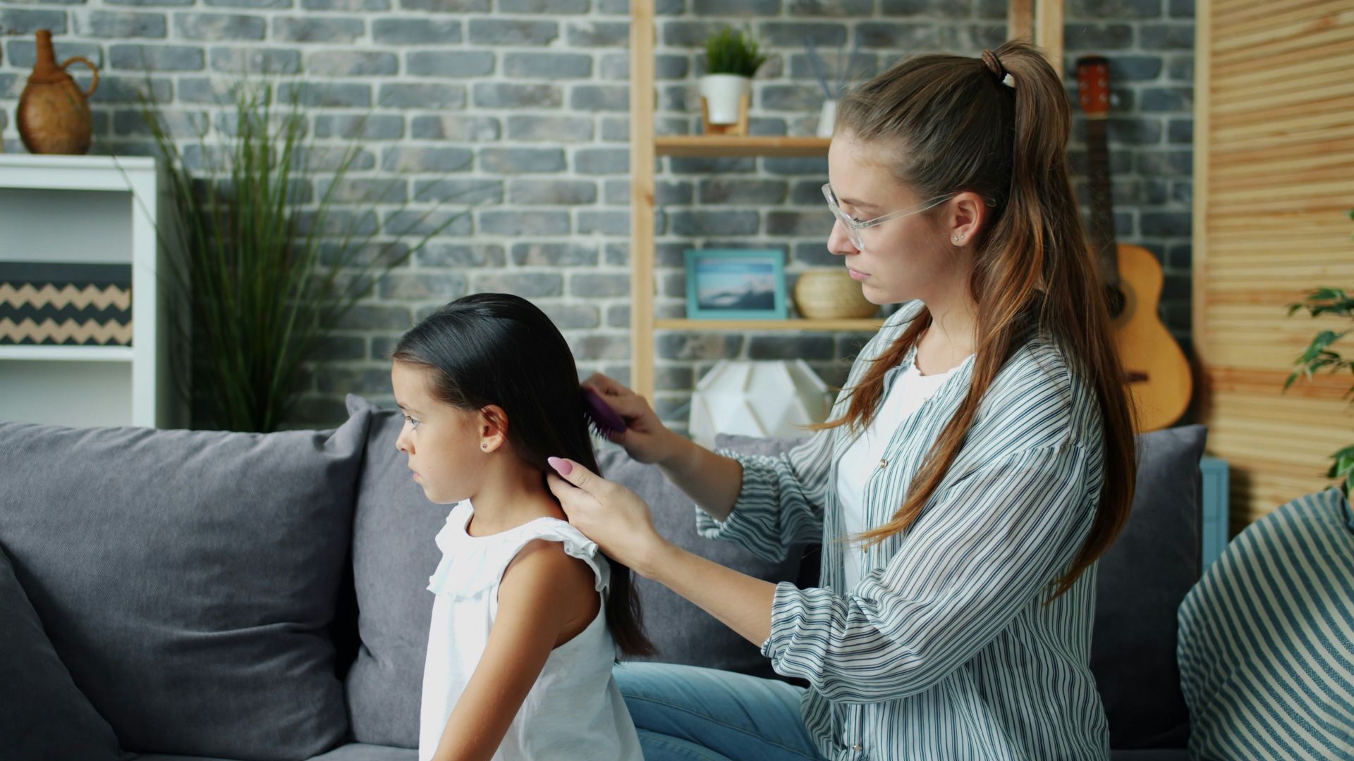 Mother combs her daughter's long dark hair.