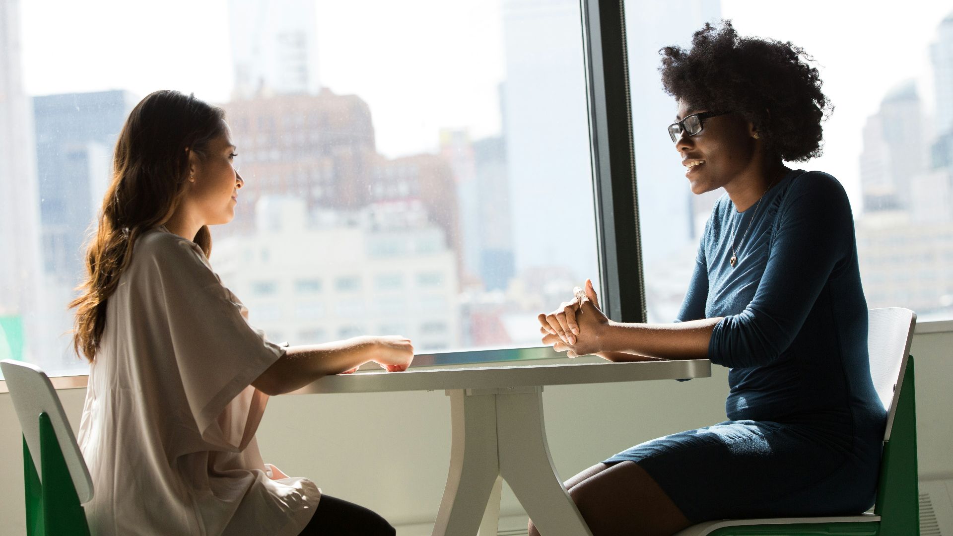 two women sitting beside table and talking