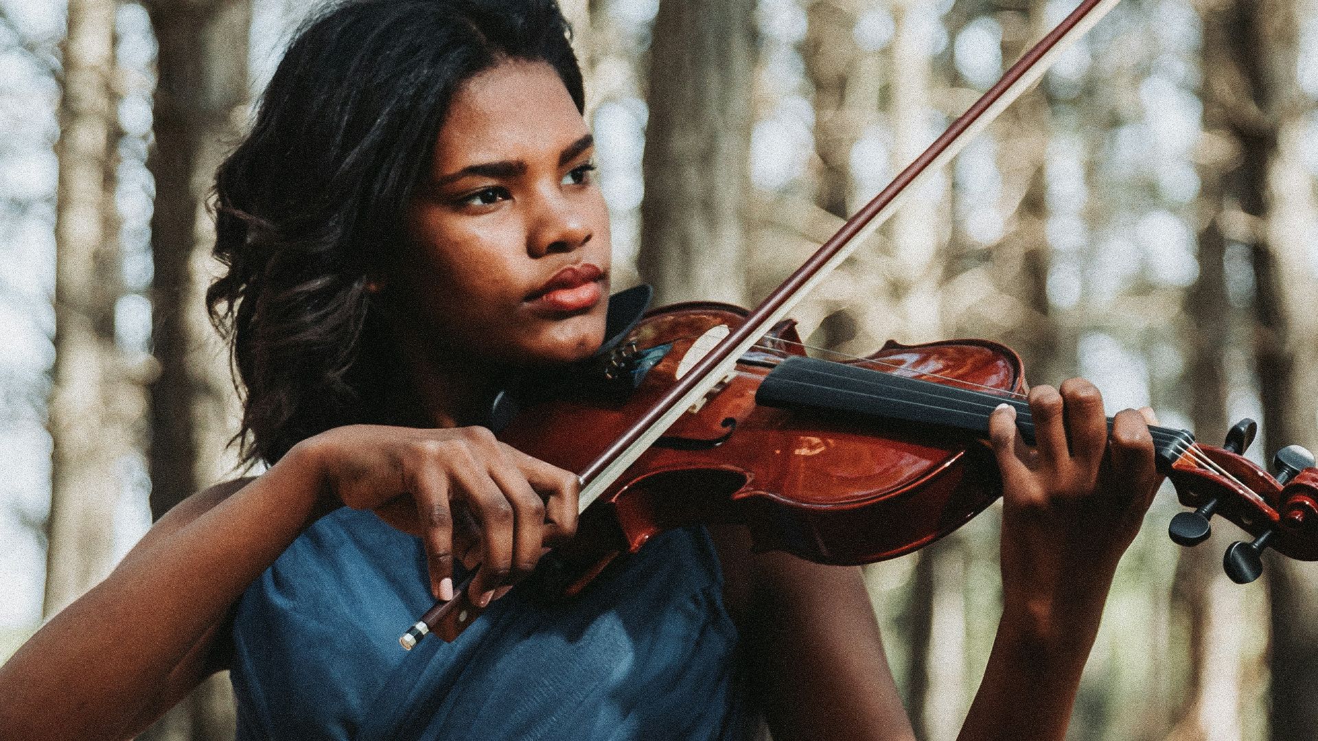 a woman in a blue dress playing a violin