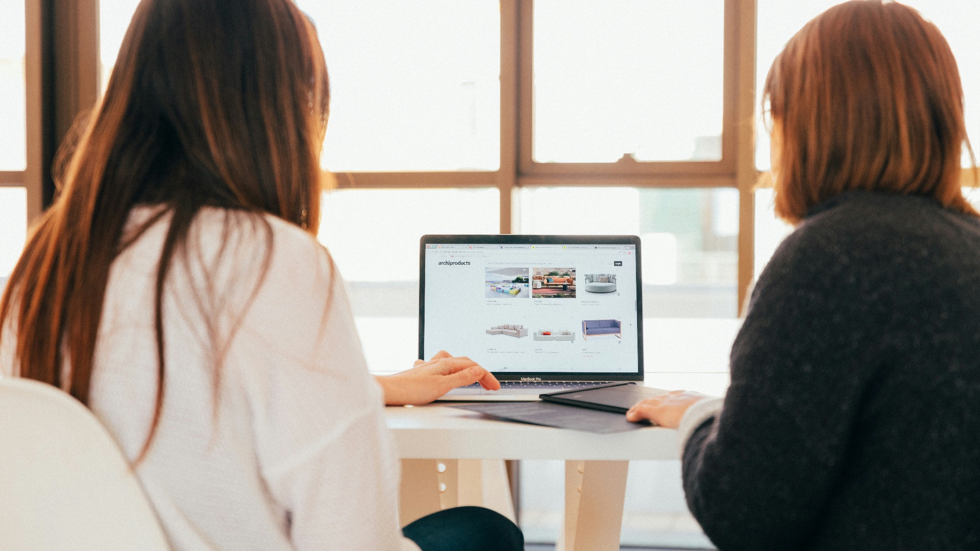 two women talking while looking at laptop computer
