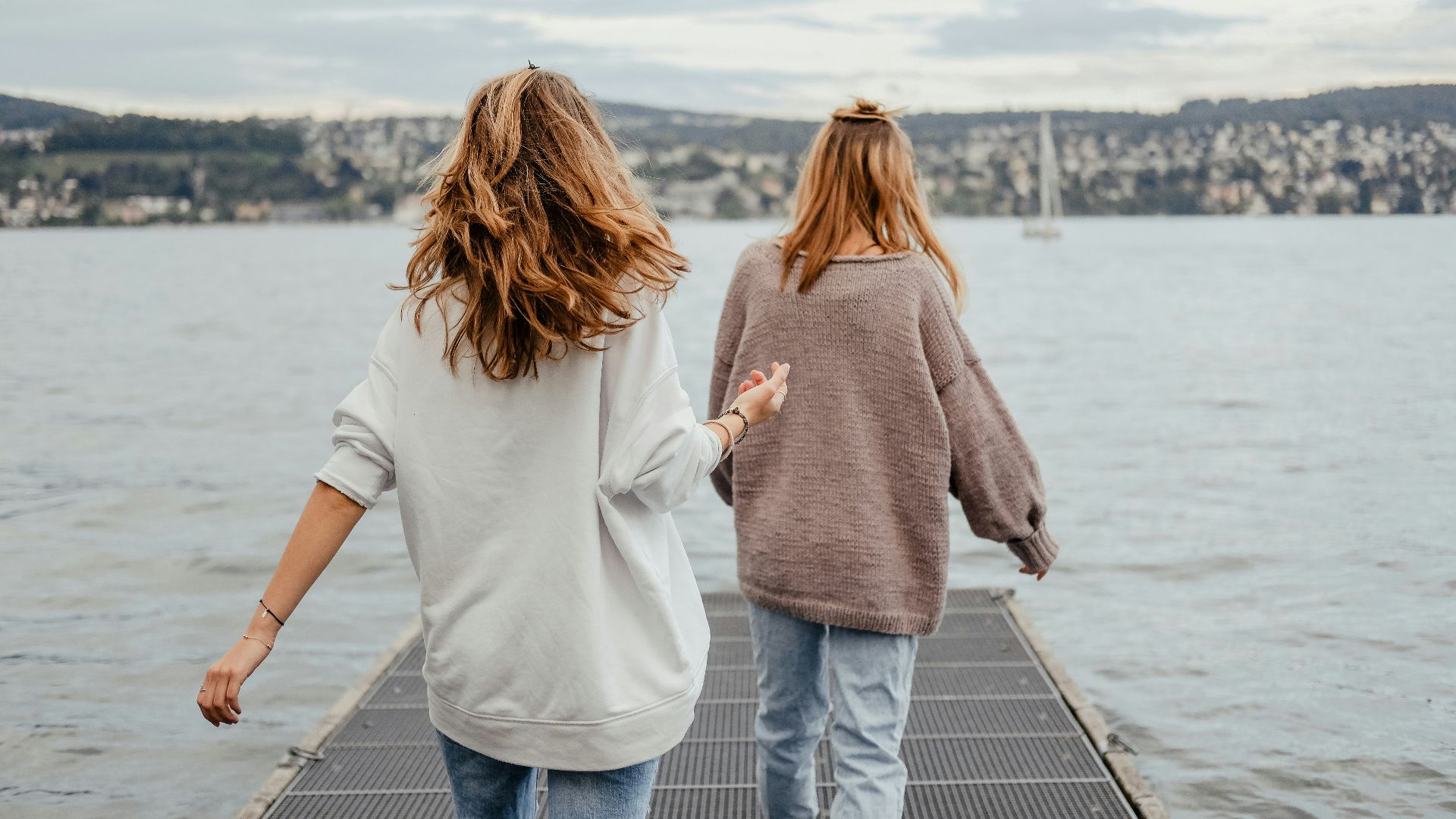 two women standing on dock front of sea at daytime