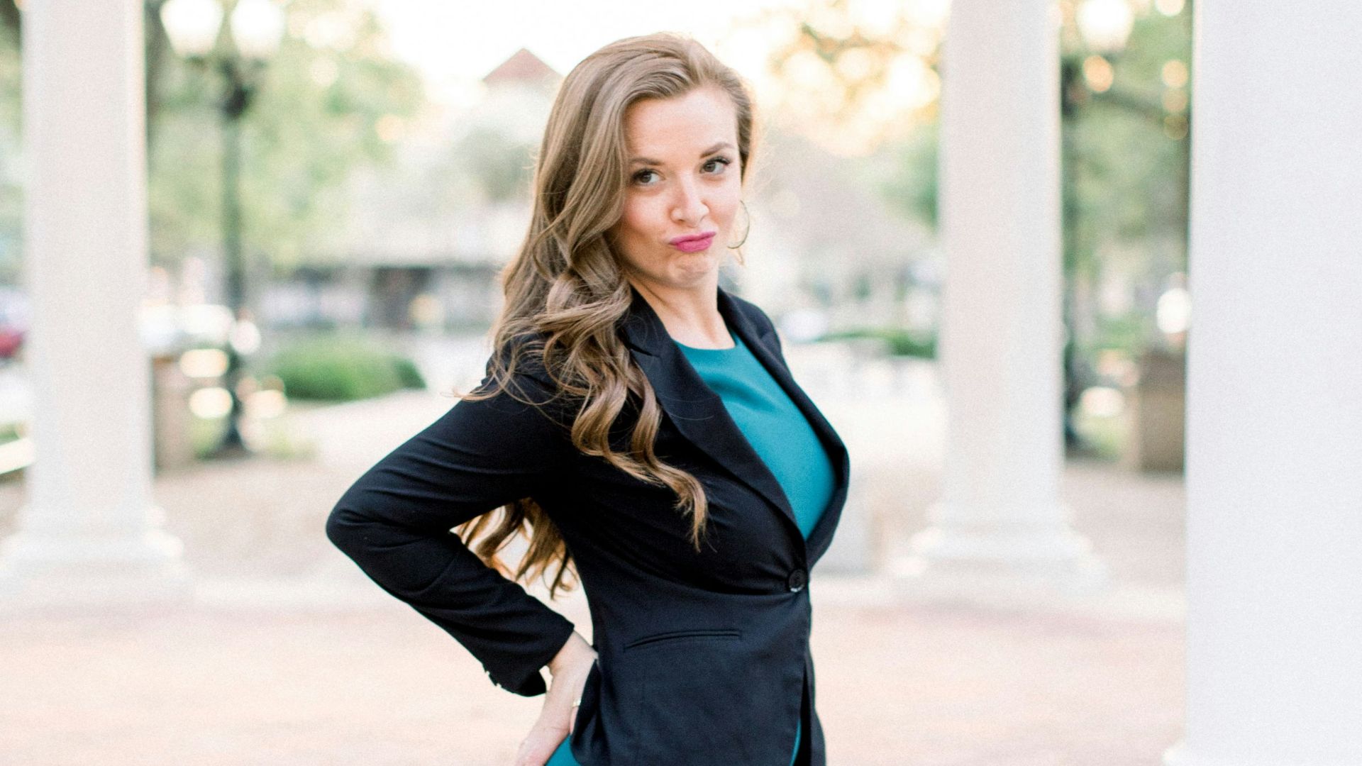 woman in black leather jacket and blue mini skirt standing on gray concrete floor during daytime