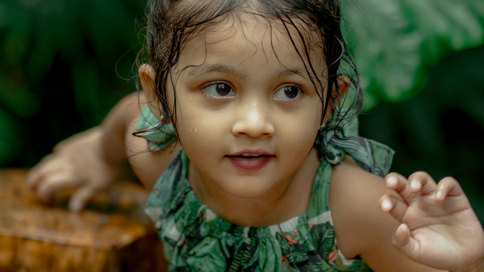 a little girl standing next to a tree stump