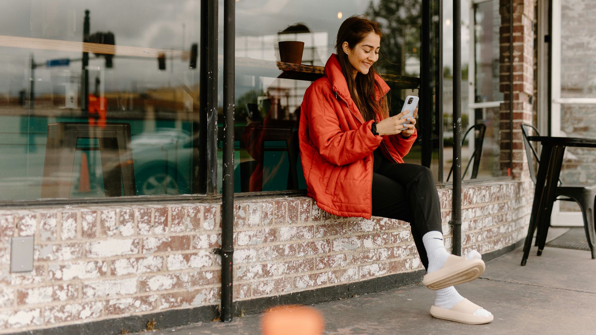 a woman sitting on a window sill looking at her cell phone