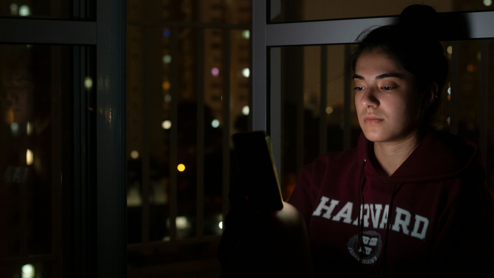 woman in red and white hoodie standing near glass window