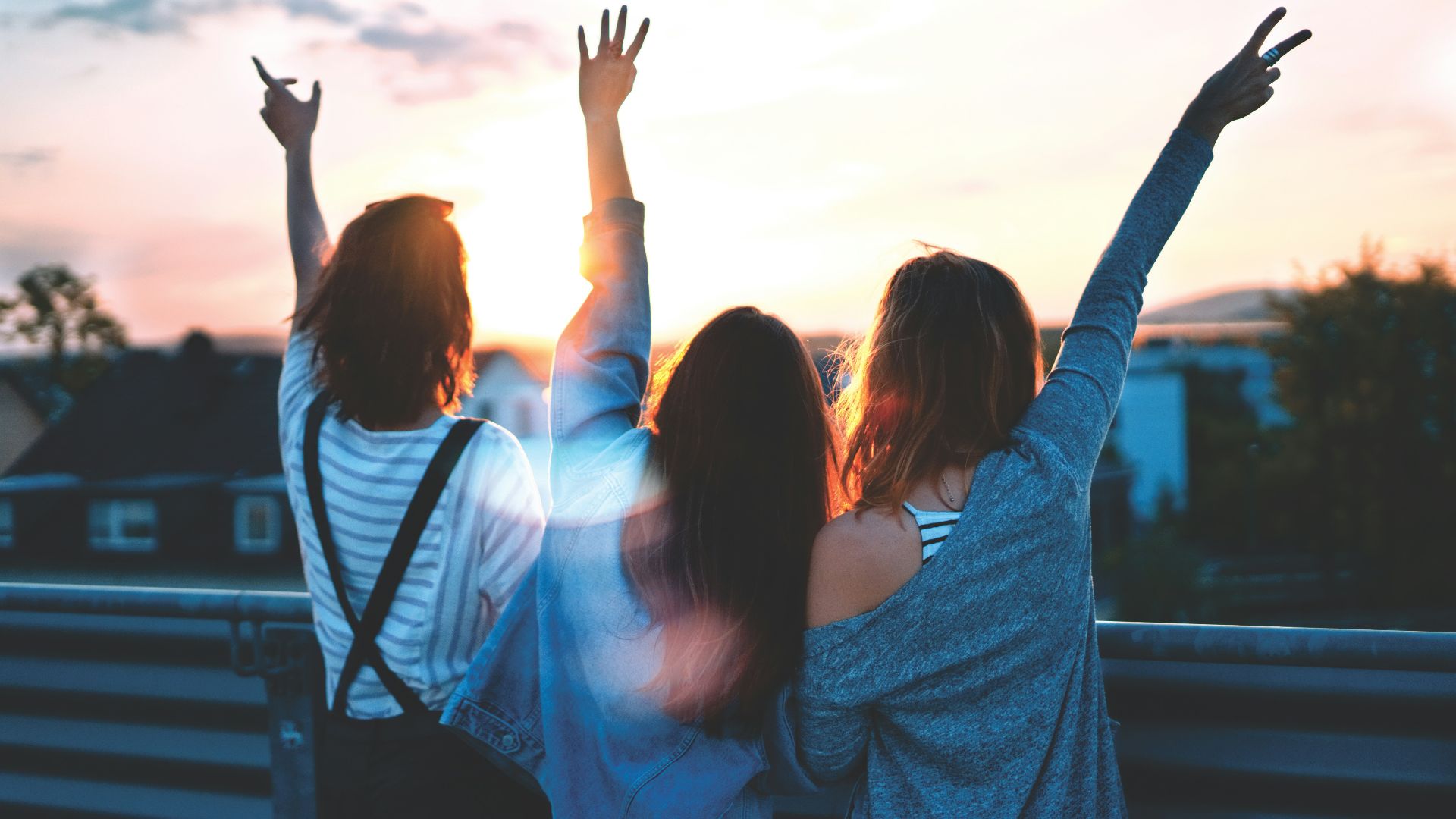 photo of three women lifting there hands \
