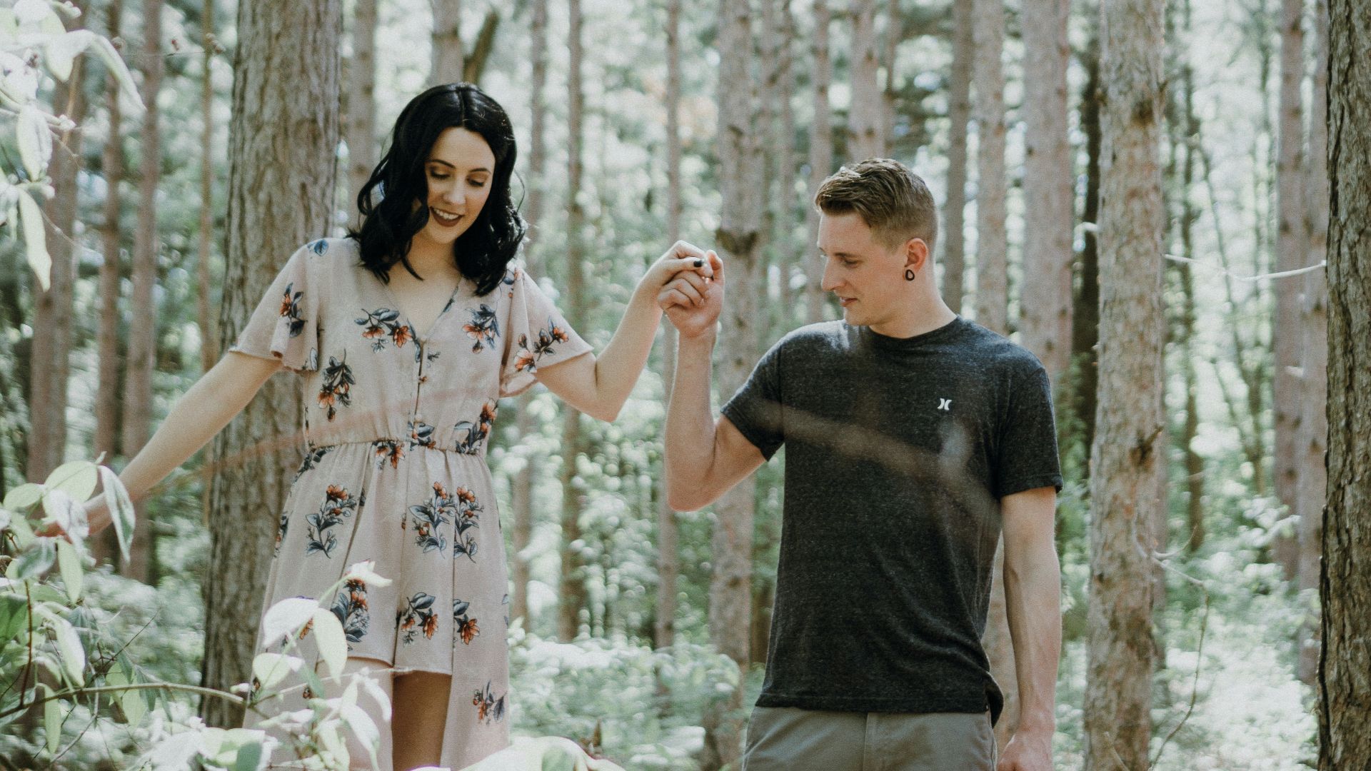 man holding hands with woman near trees