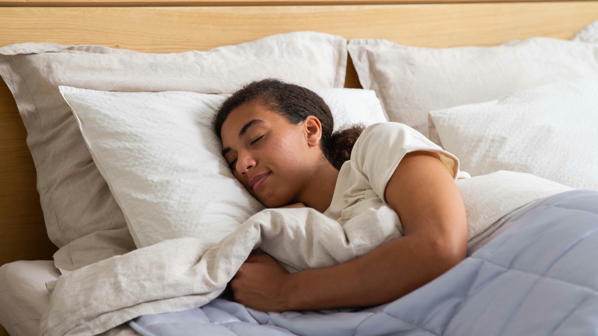 a young girl sleeping in a bed with white sheets
