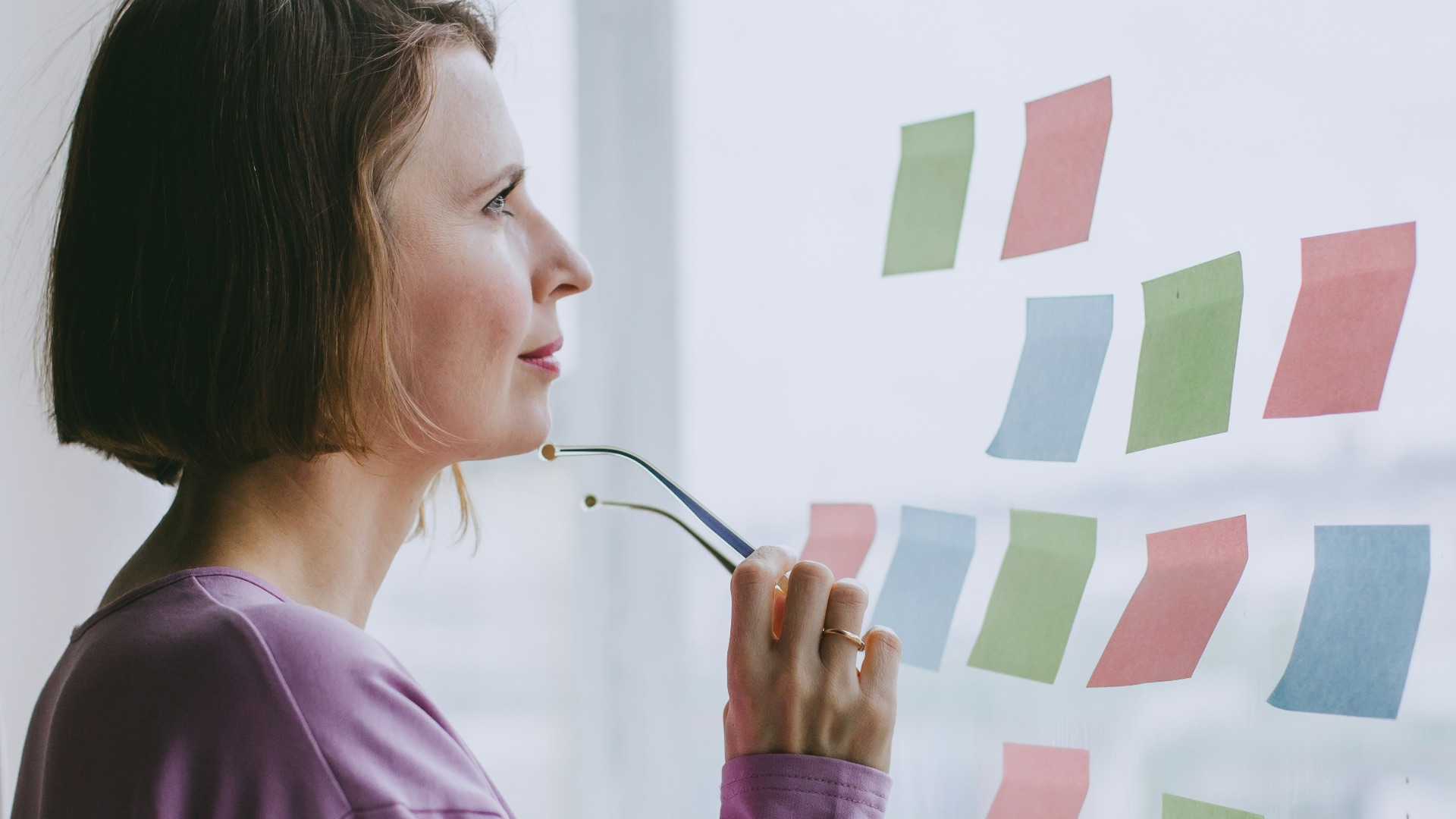 a woman looking out a window with sticky notes on it
