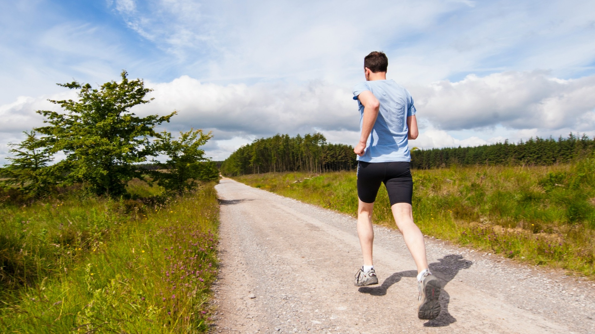 man running on road near grass field
