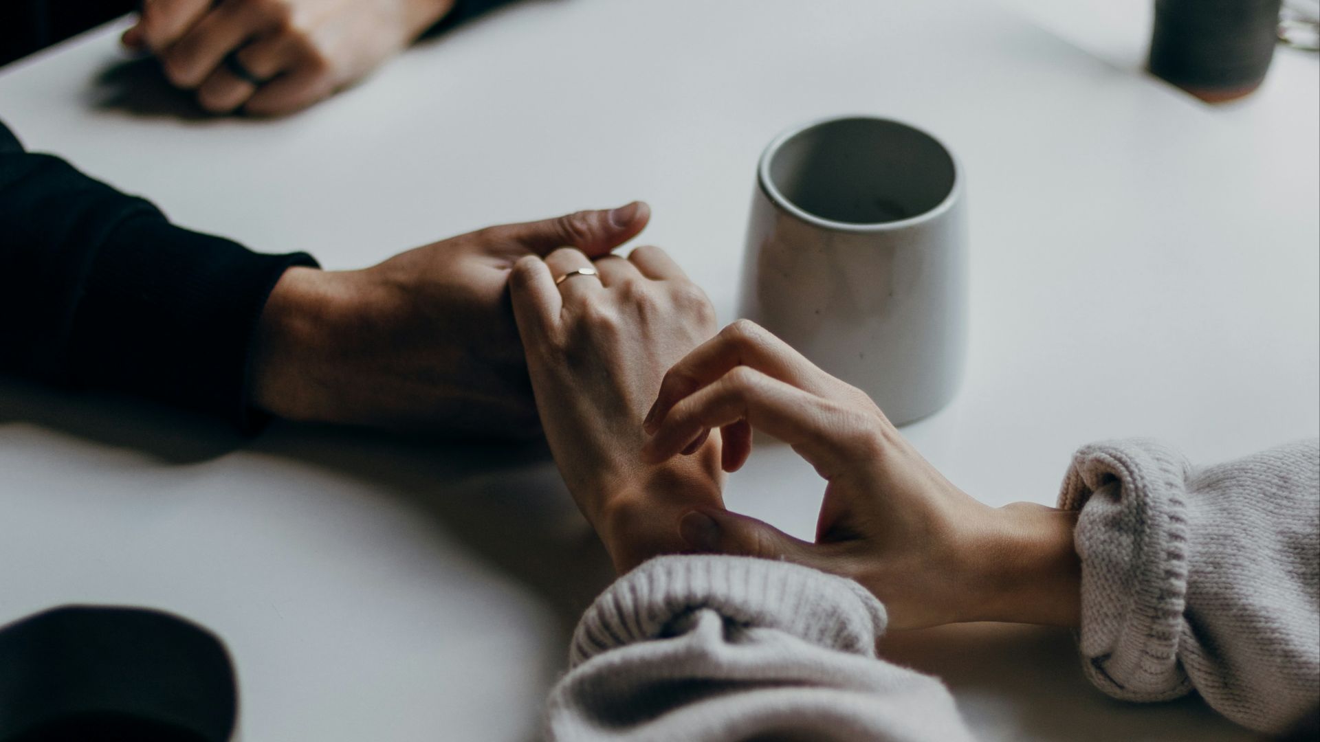 person in black long sleeve shirt holding white ceramic mug