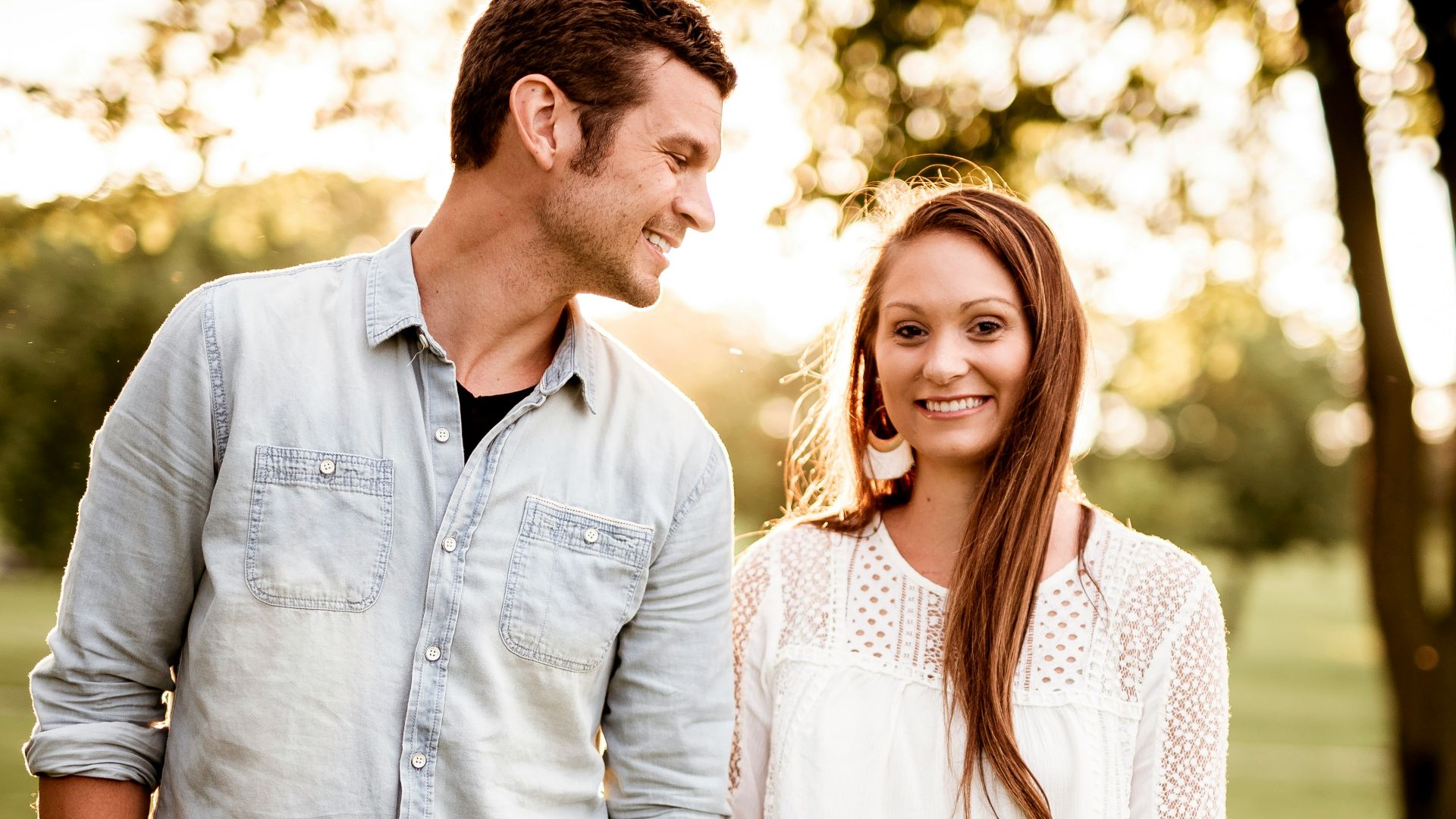 man holding hand of woman standing near tree