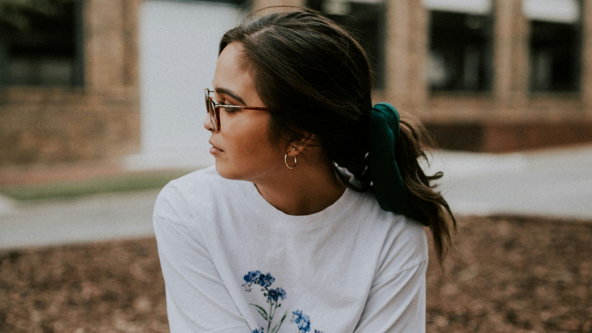 shallow focus photo of woman in white crew-neck T-shirt sitting on concrete bench
