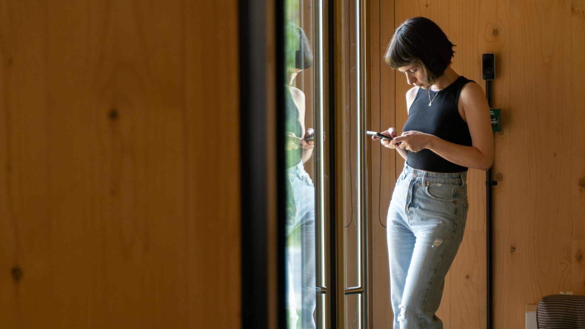a woman standing in front of a door looking at her cell phone
