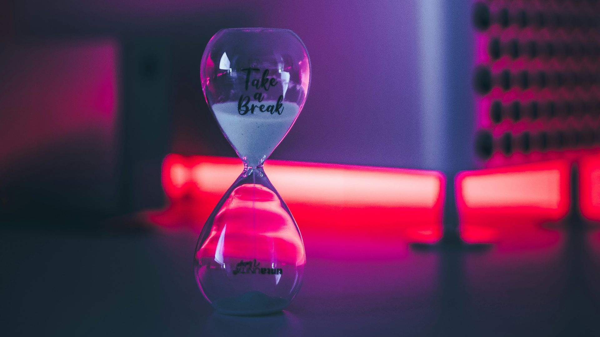 clear glass hour glass with pink light