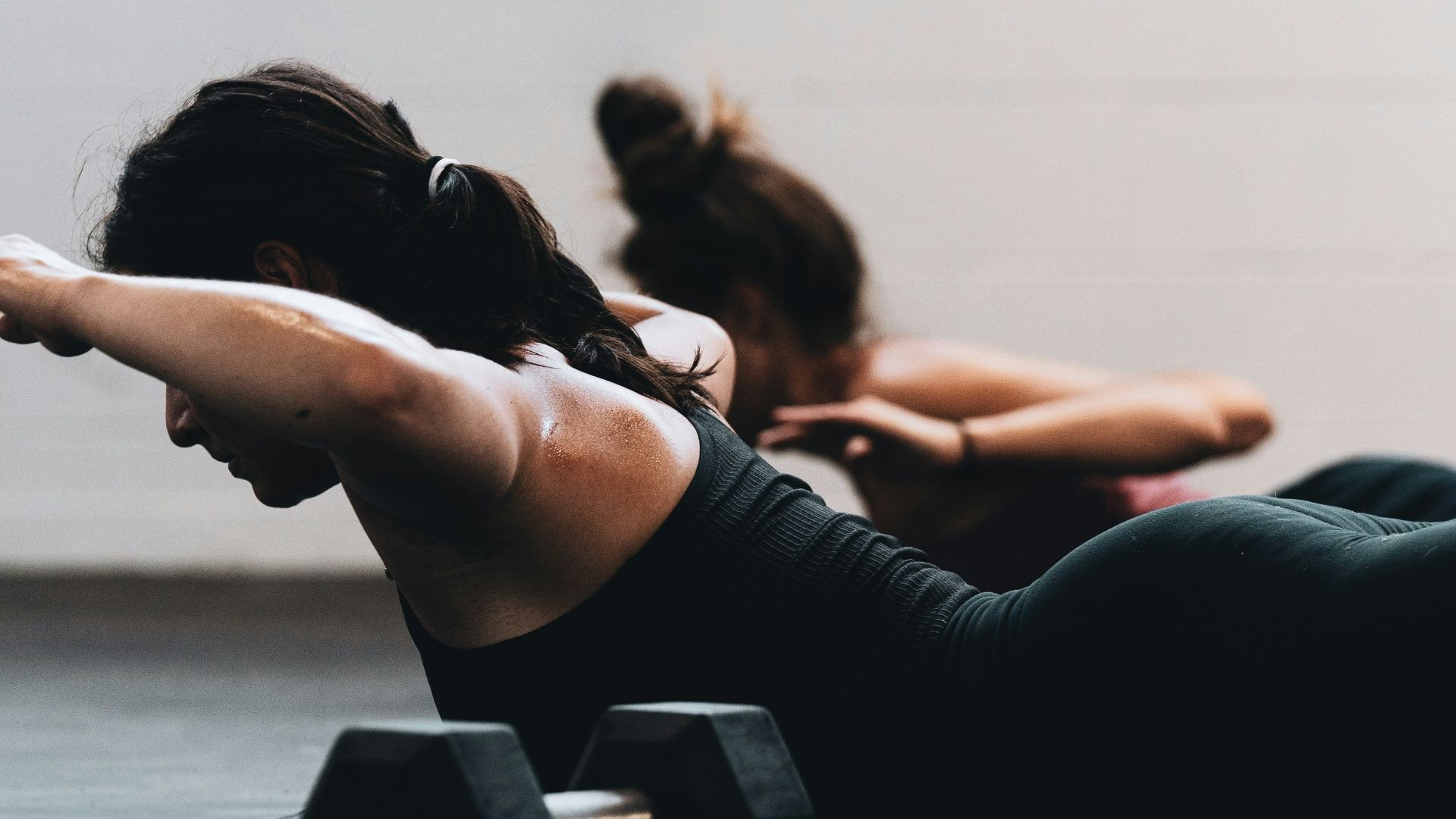 woman in black tank top and black leggings lying on black floor