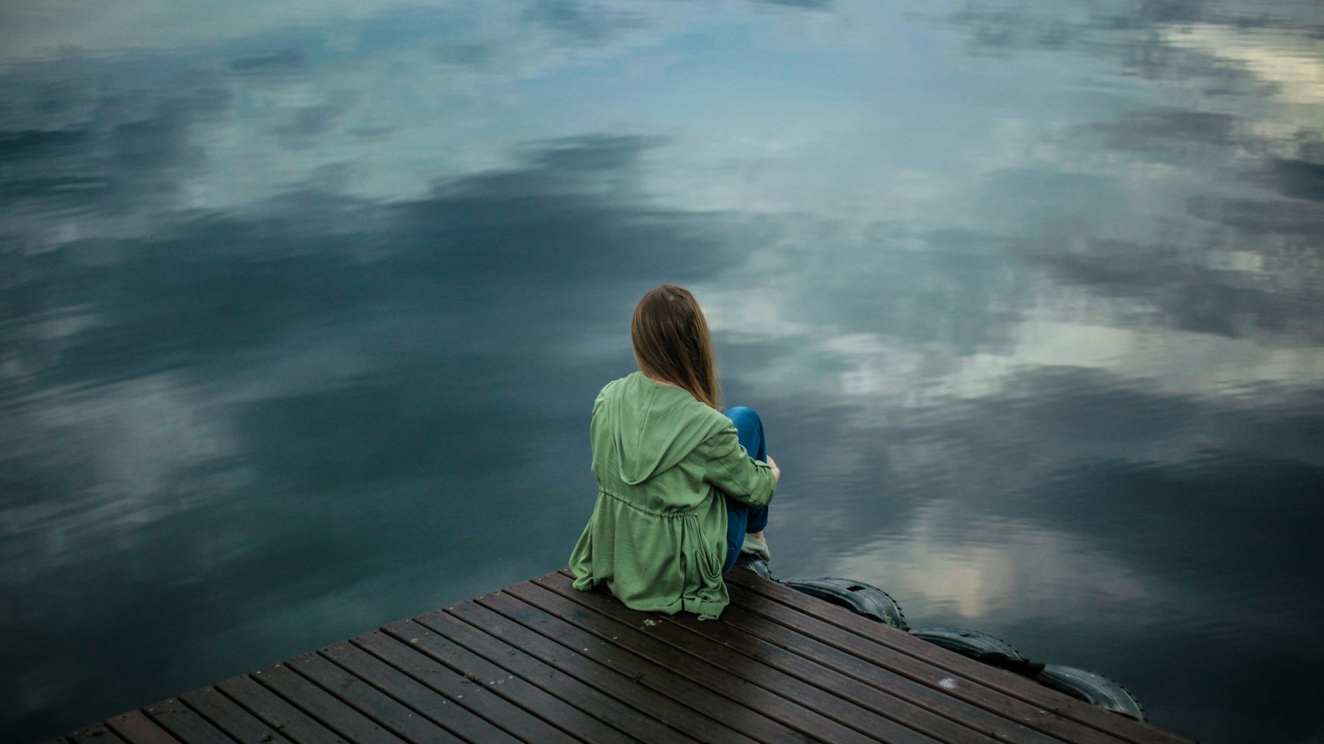 woman sitting on dock near body of water