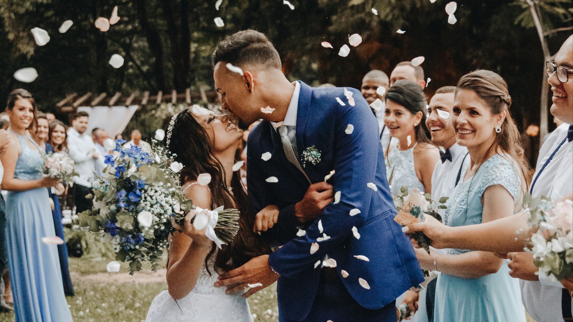 man in blue suit kissing woman in white wedding dress