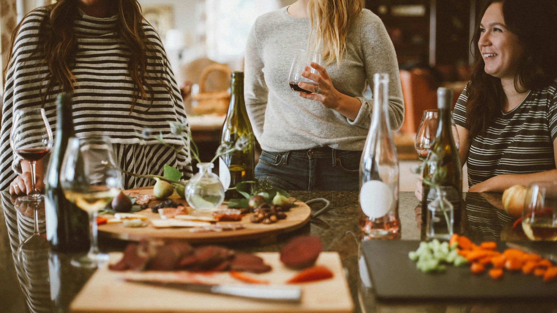 two woman standing beside woman sitting in front of table
