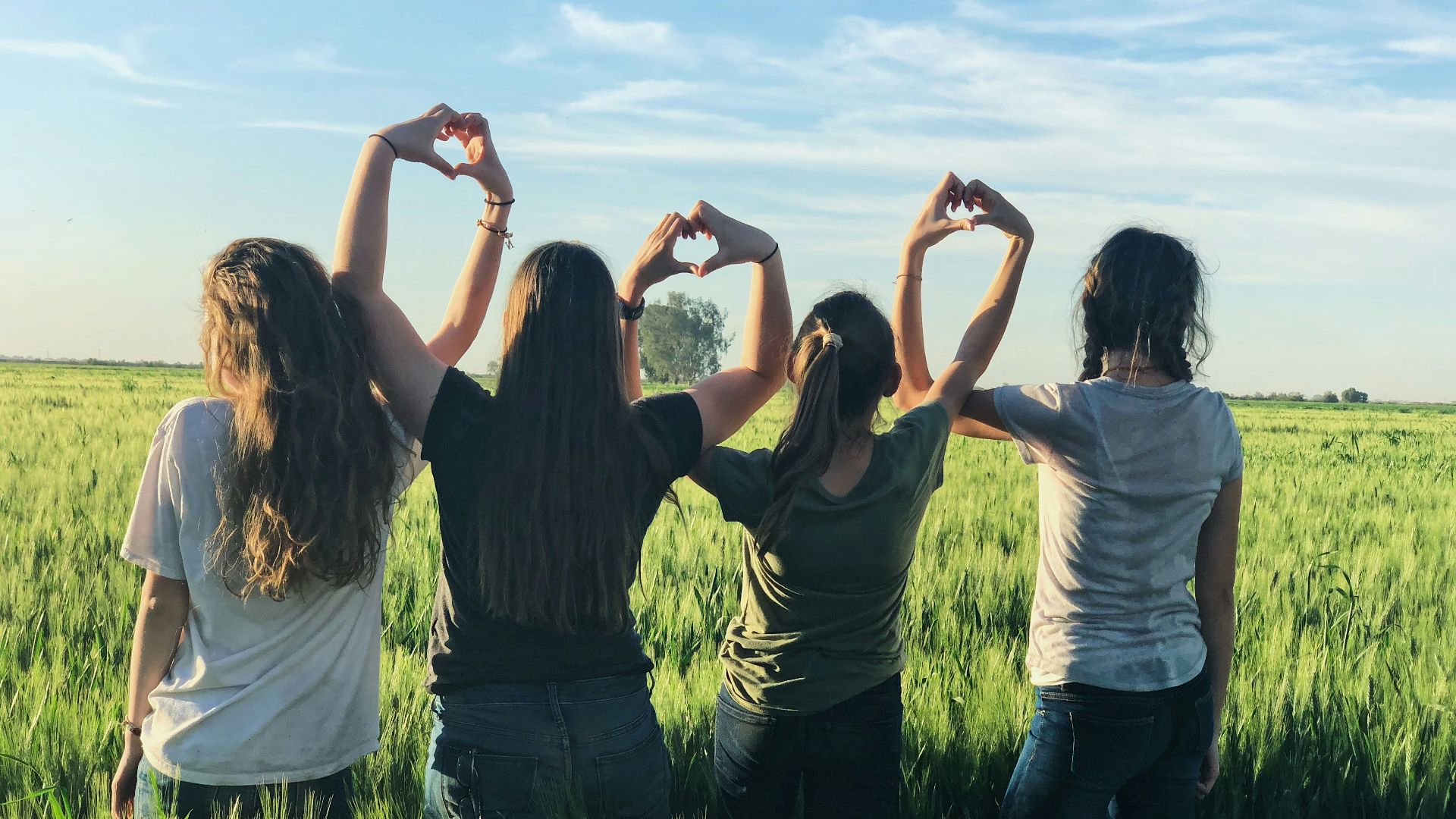 women forming heart gestures during daytime