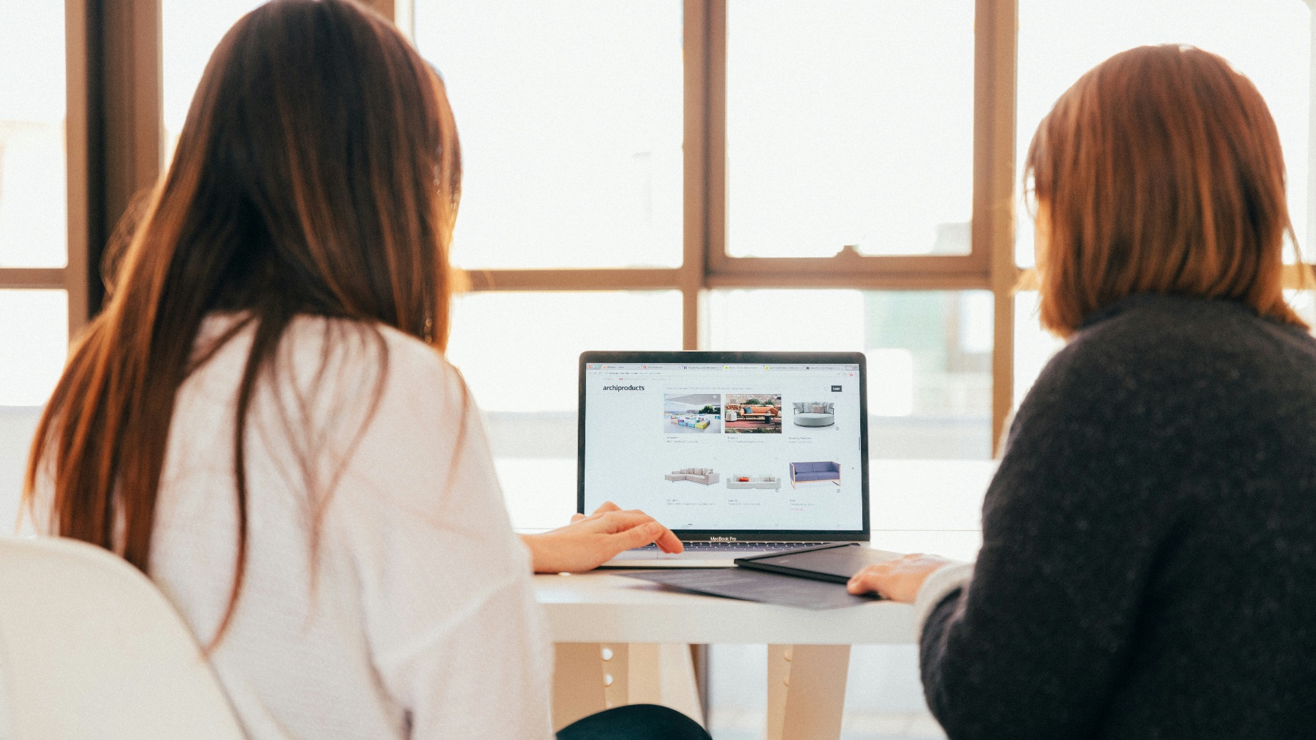two women talking while looking at laptop computer