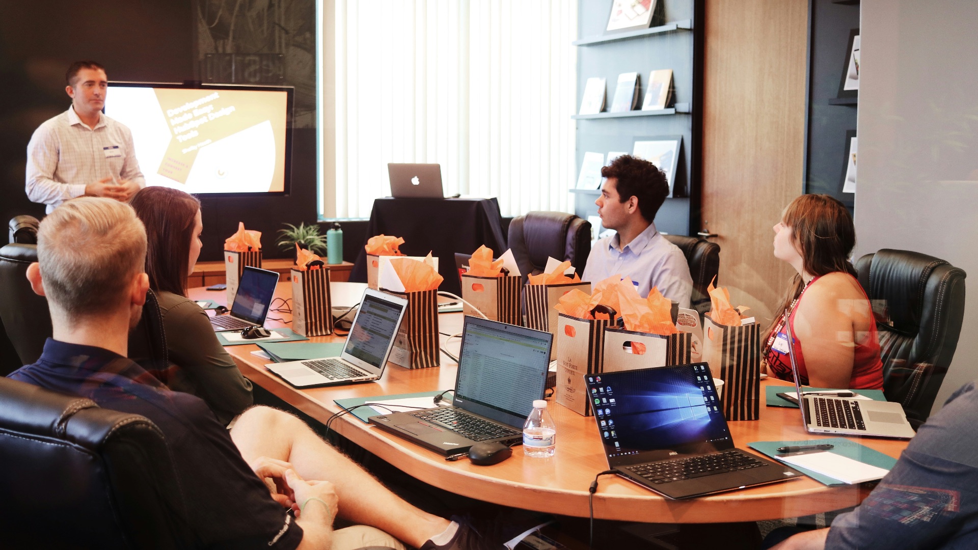 man standing in front of people sitting beside table with laptop computers