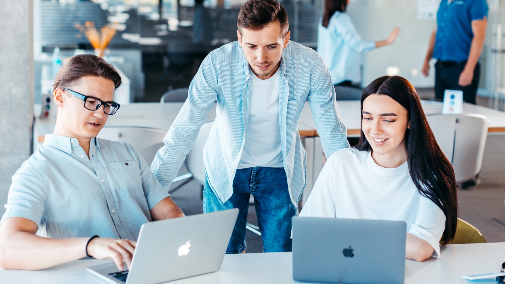 a group of people sitting around a table with laptops