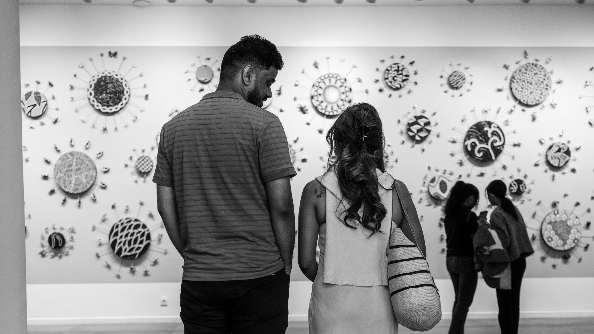 Couple viewing circular art on gallery wall