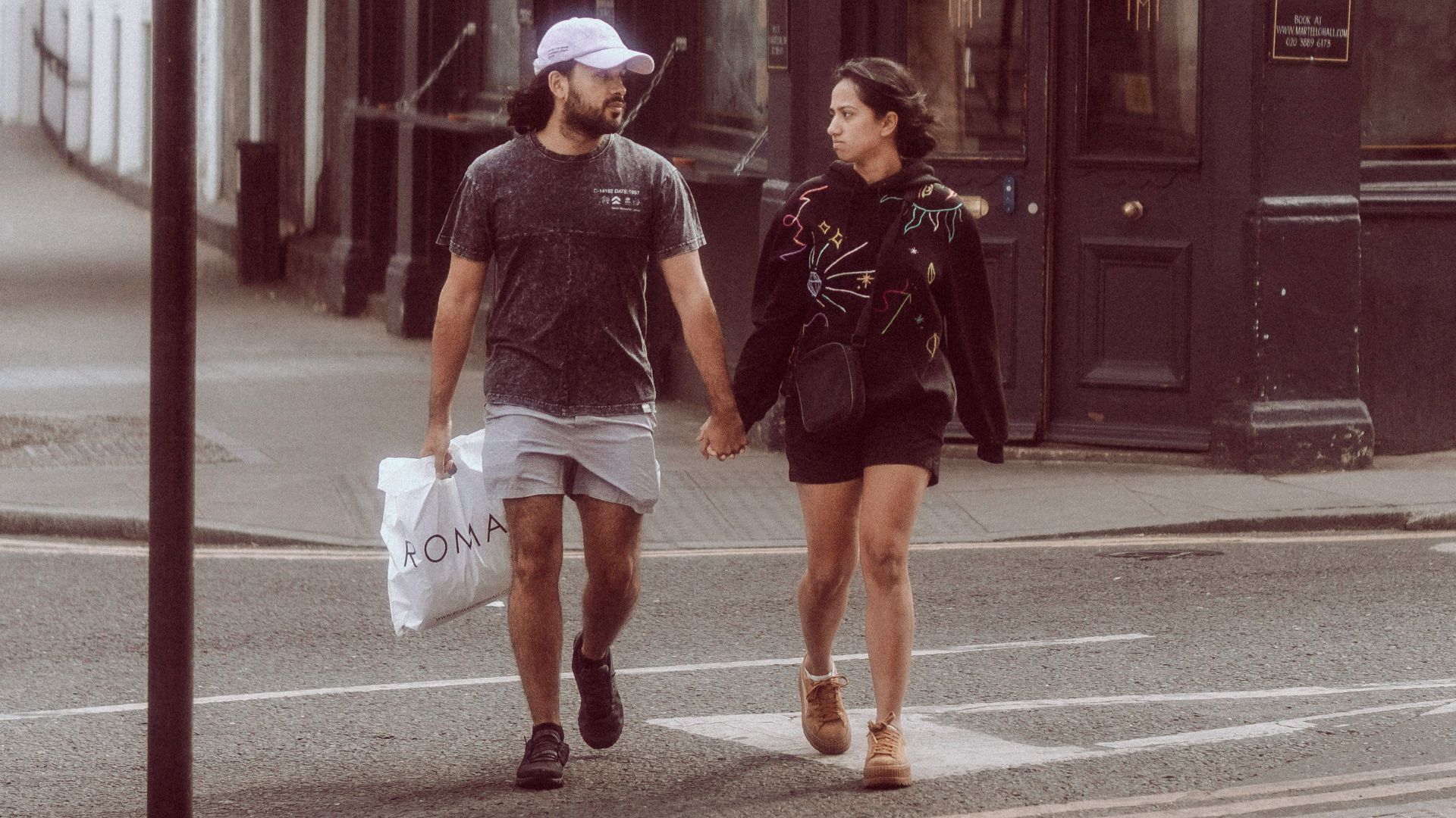 a man and woman walking down a street holding hands
