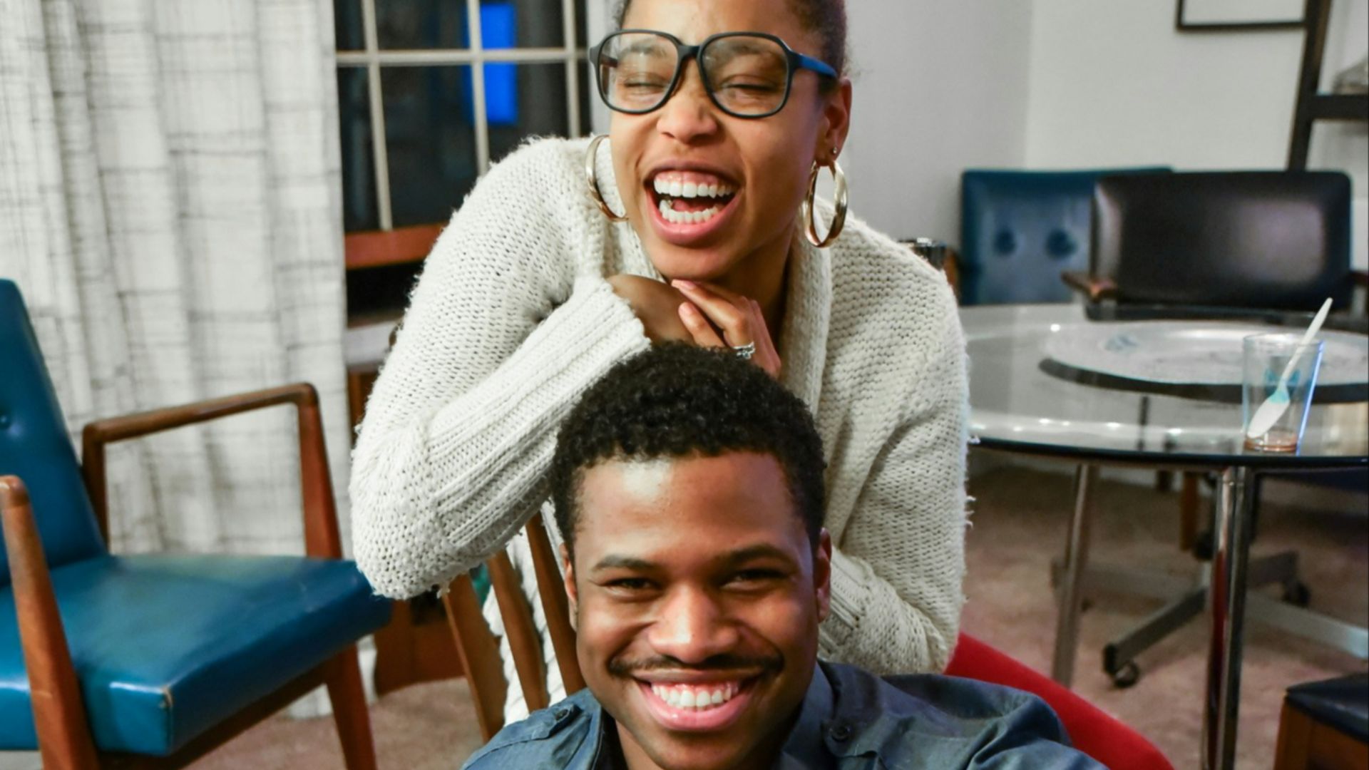 man sitting on floor beside woman smiling inside white painted room
