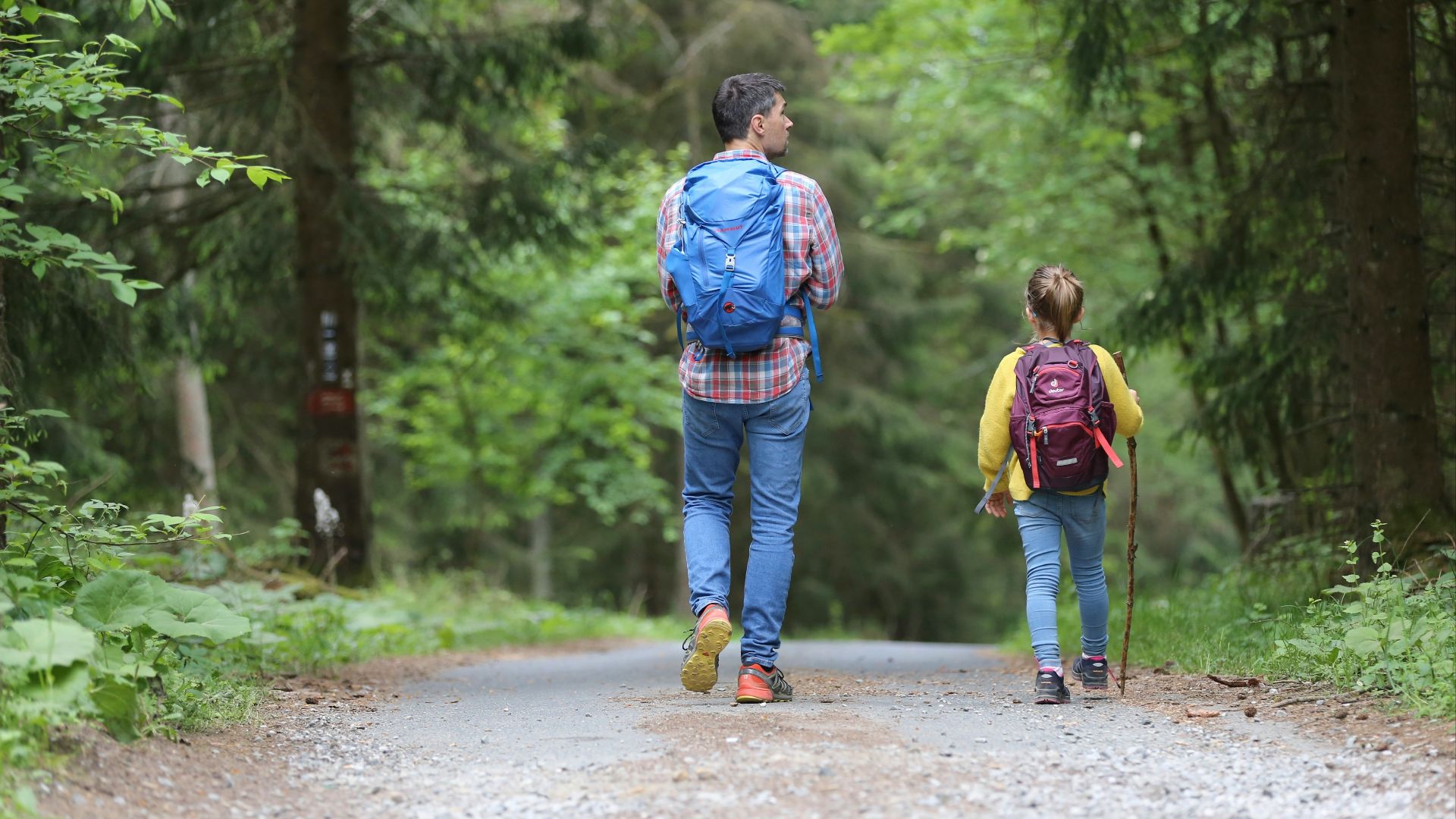 man in blue jacket and blue denim jeans walking on dirt road during daytime