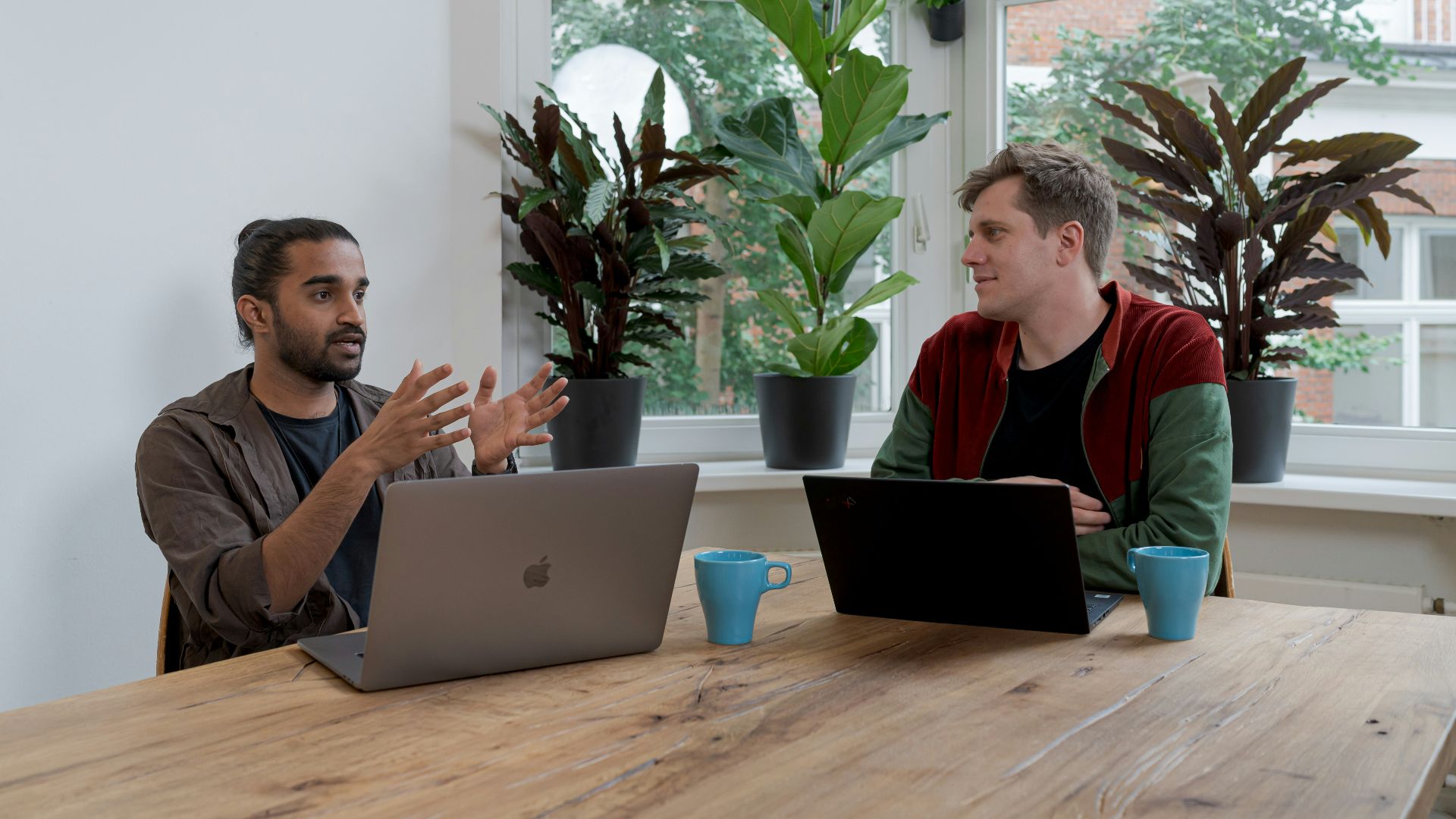 man in red and black crew neck t-shirt using silver macbook