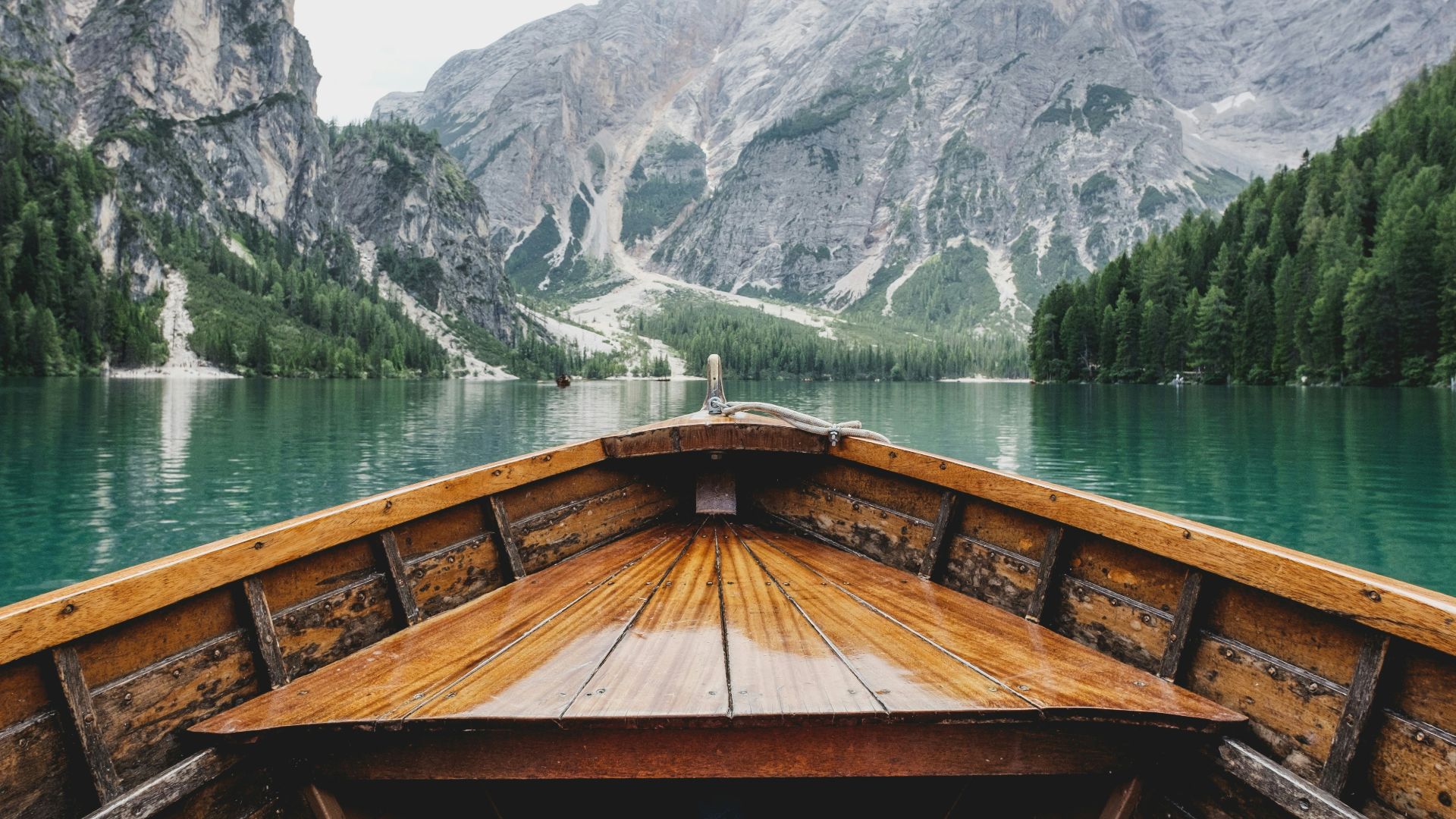 brown wooden boat moving towards the mountain