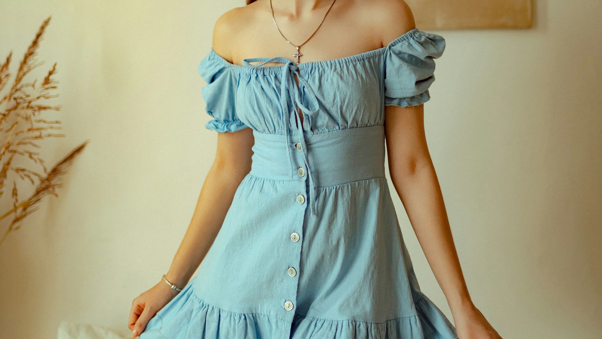 Young woman in a light blue dress standing indoors