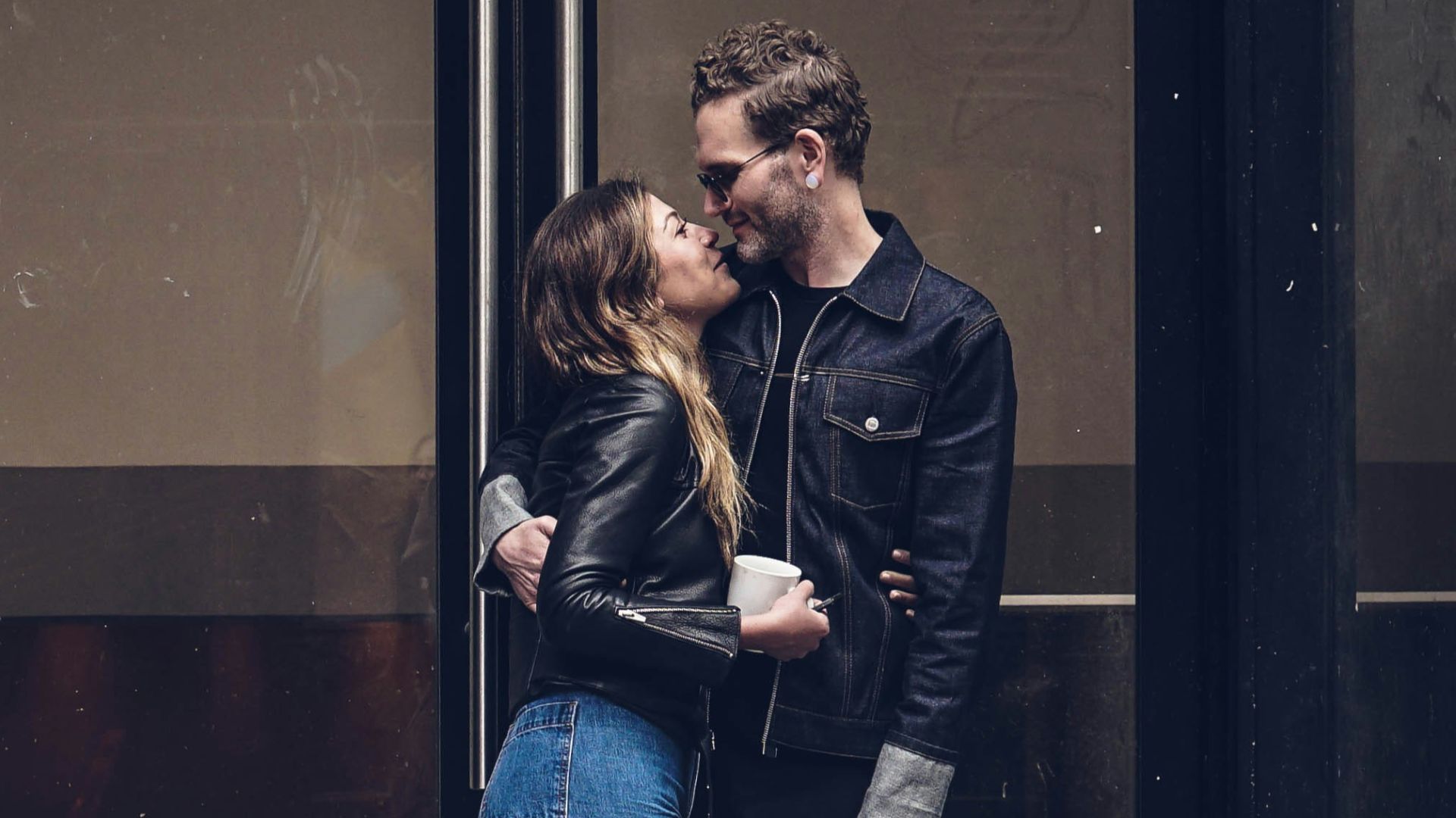 photo of man and woman kissing beside glass doors