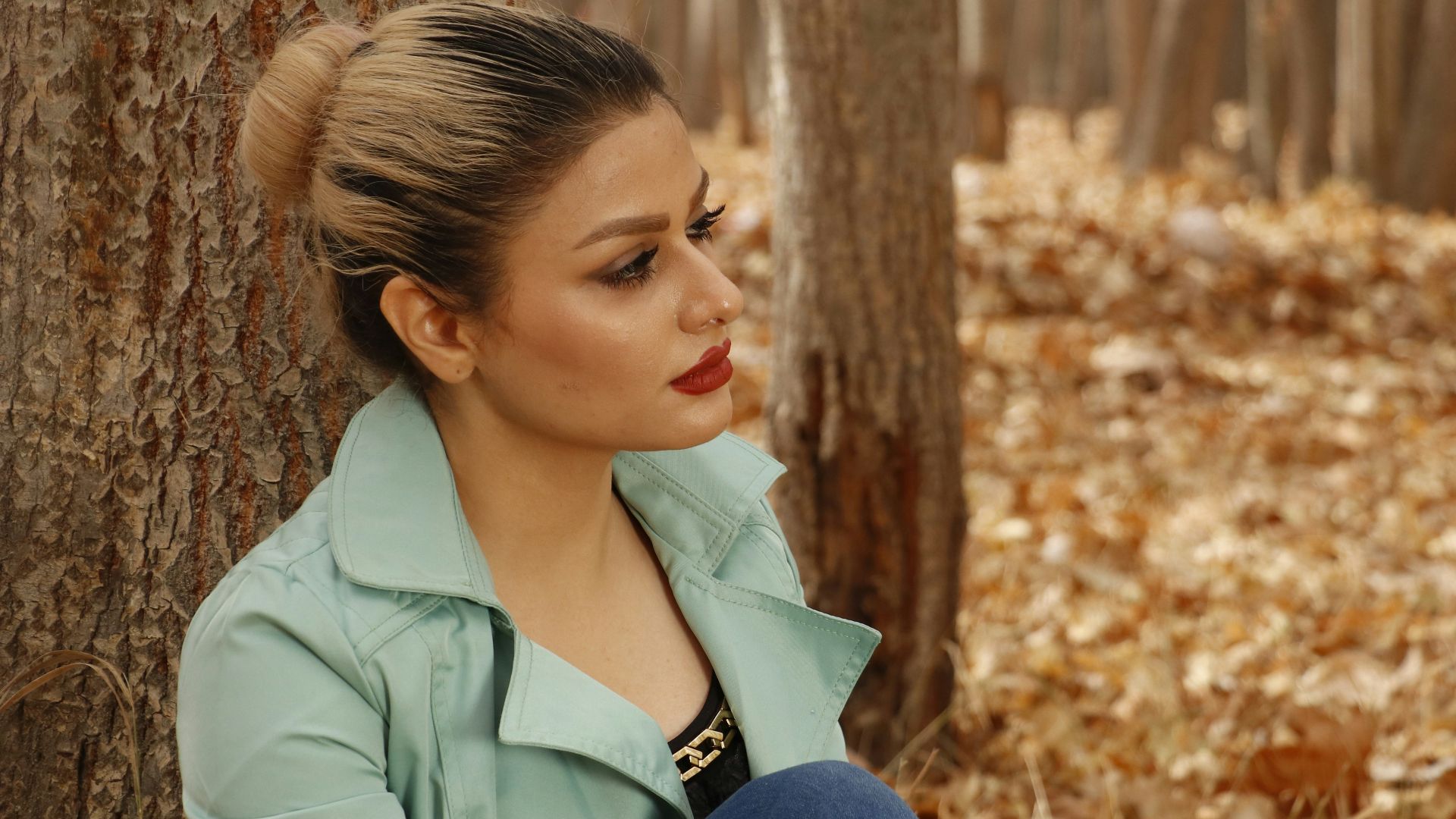 a woman sitting on the ground next to a tree