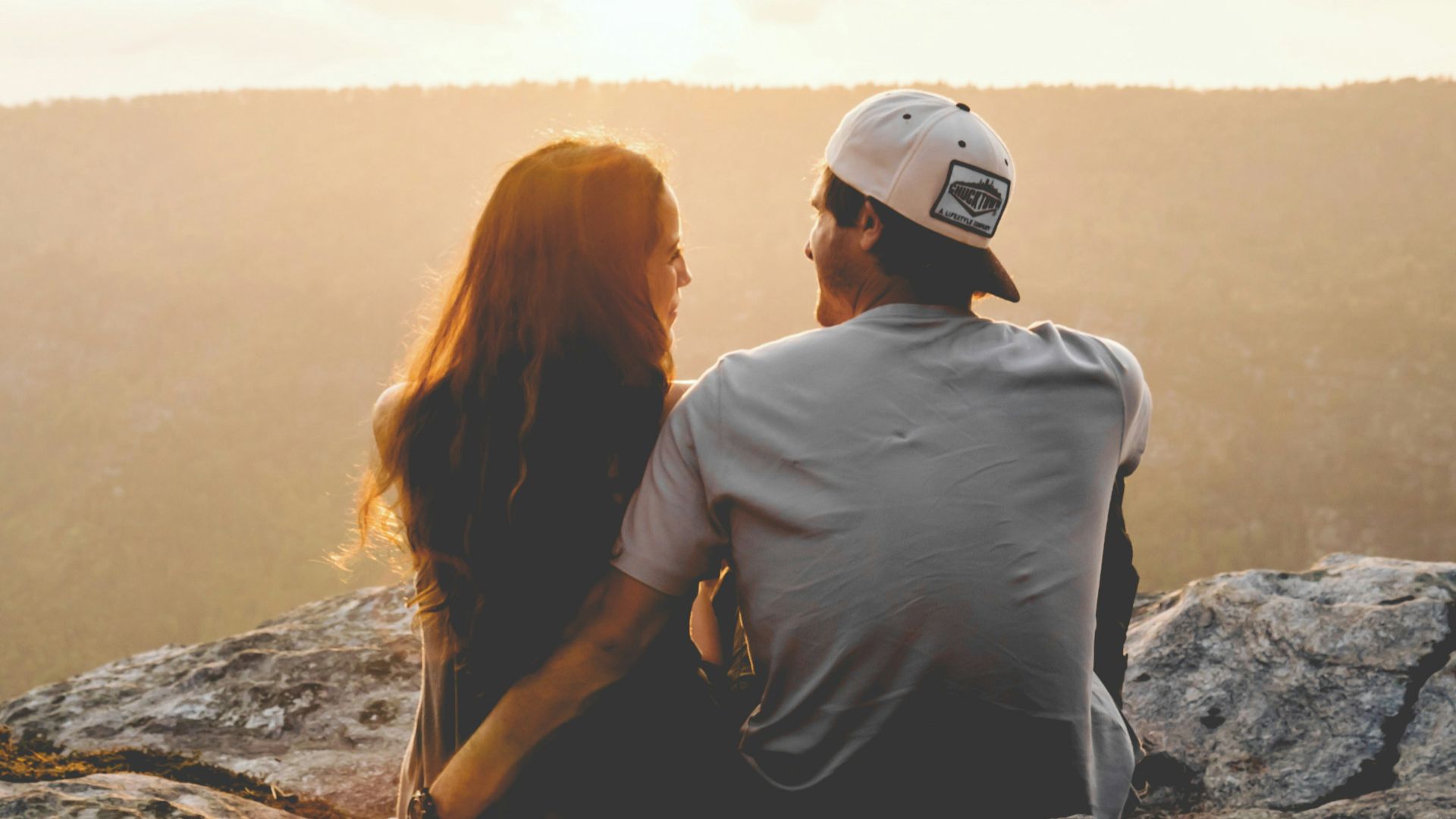 man and woman sitting on rock during daytime